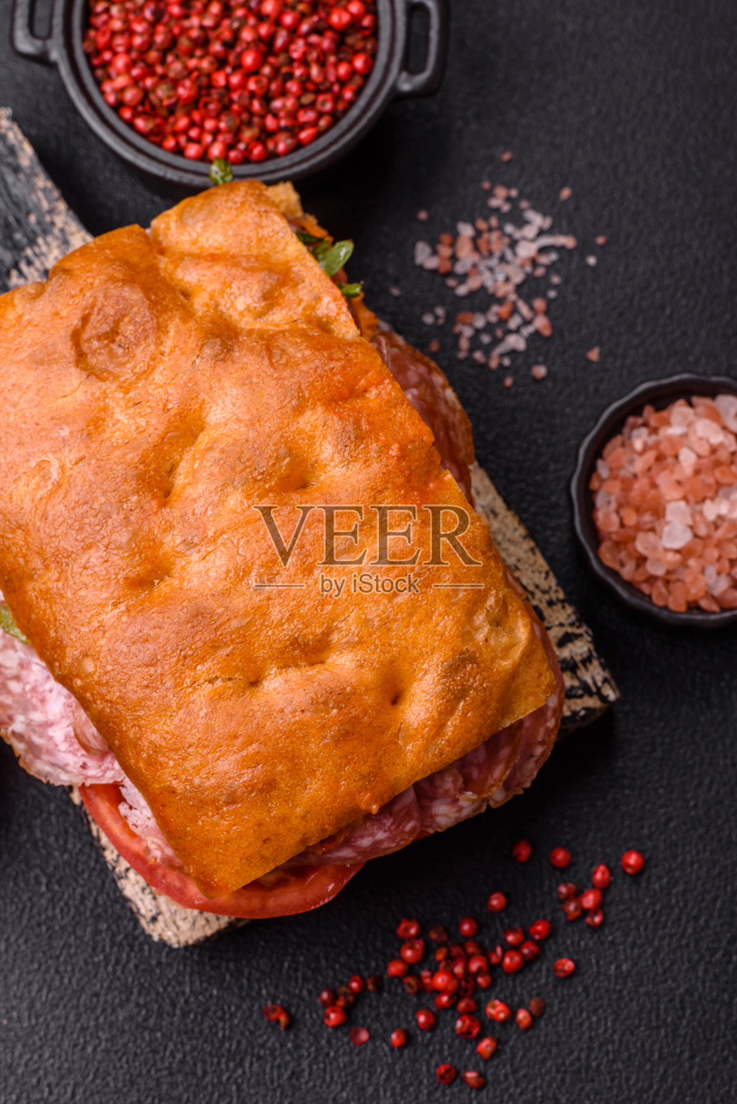 意大利薄饼配香肠、奶酪、西红柿、芝麻菜、盐、香料和草药照片摄影图片