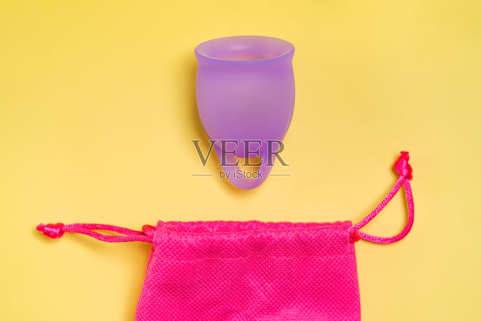 便利：紫色月经杯配储存袋，背景为黄色照片摄影图片