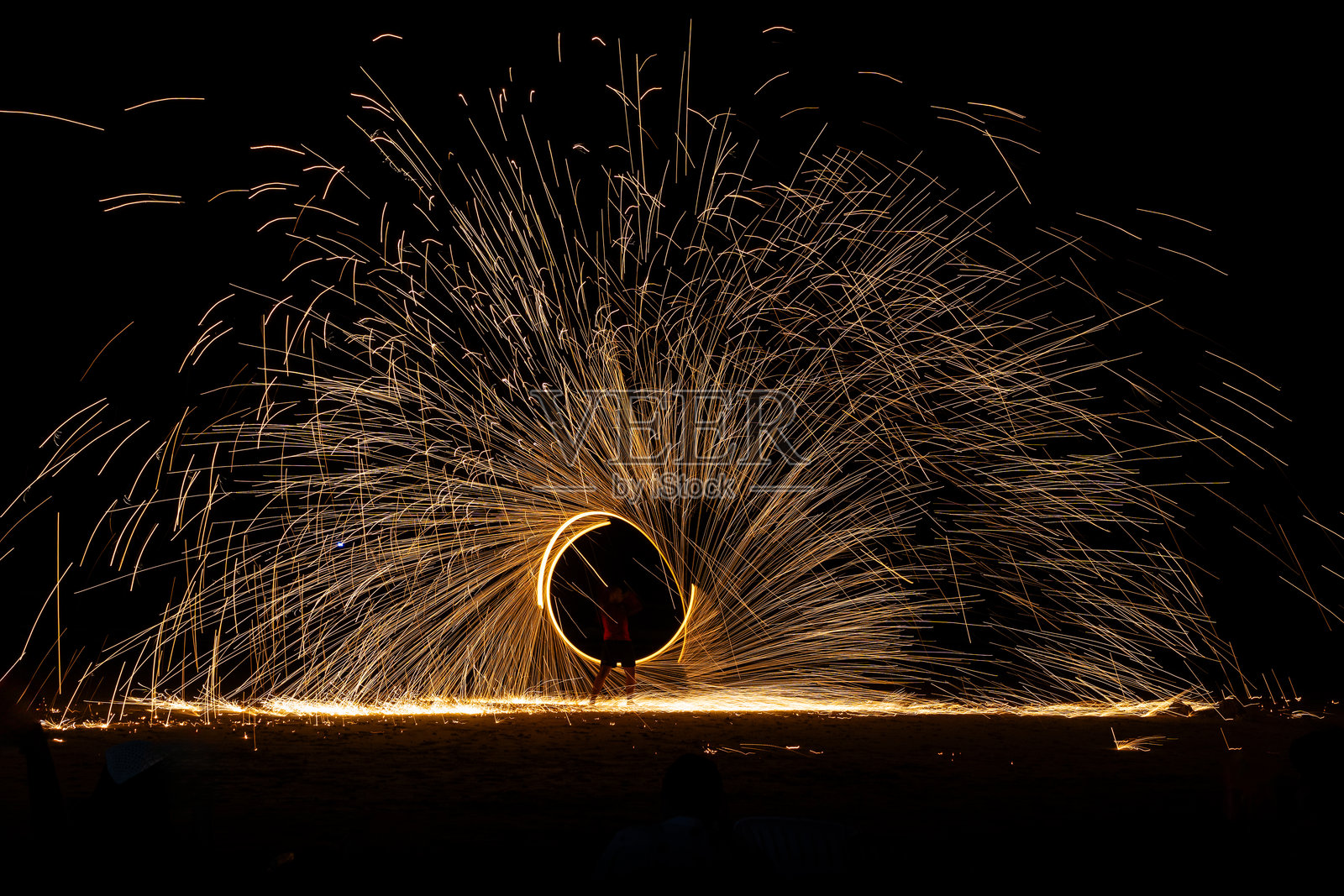 夜间地面上的秋千火舞表演，长时间曝光照片摄影图片