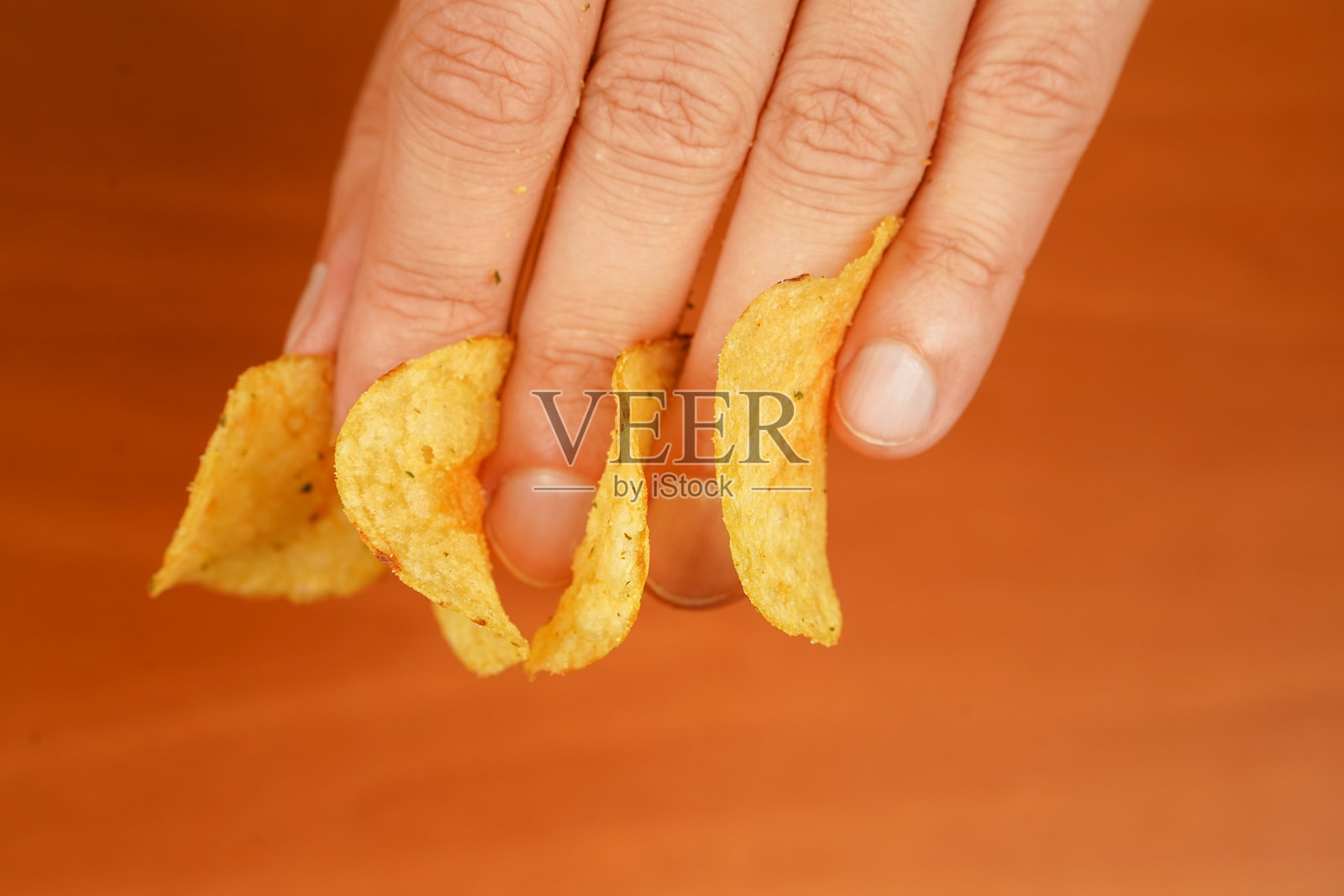 快餐。垃圾食品。不健康的生活方式。男人吃薯片。手拿薯片。卡路里。肥胖。美国食品。照片摄影图片