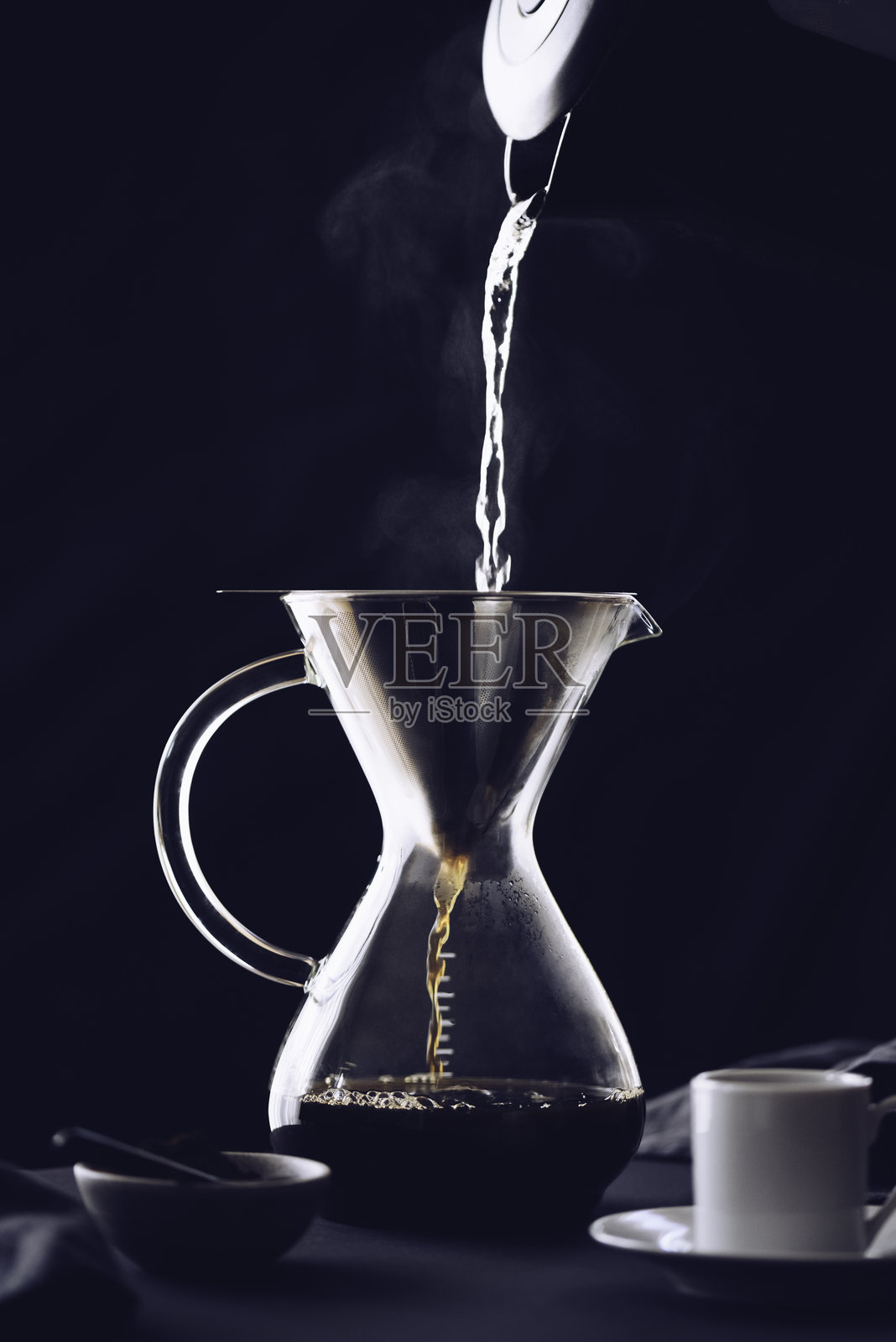 使用滤杯冲泡咖啡。咖啡通过纸滤器滴落。制作咖啡的另一种方式。照片摄影图片