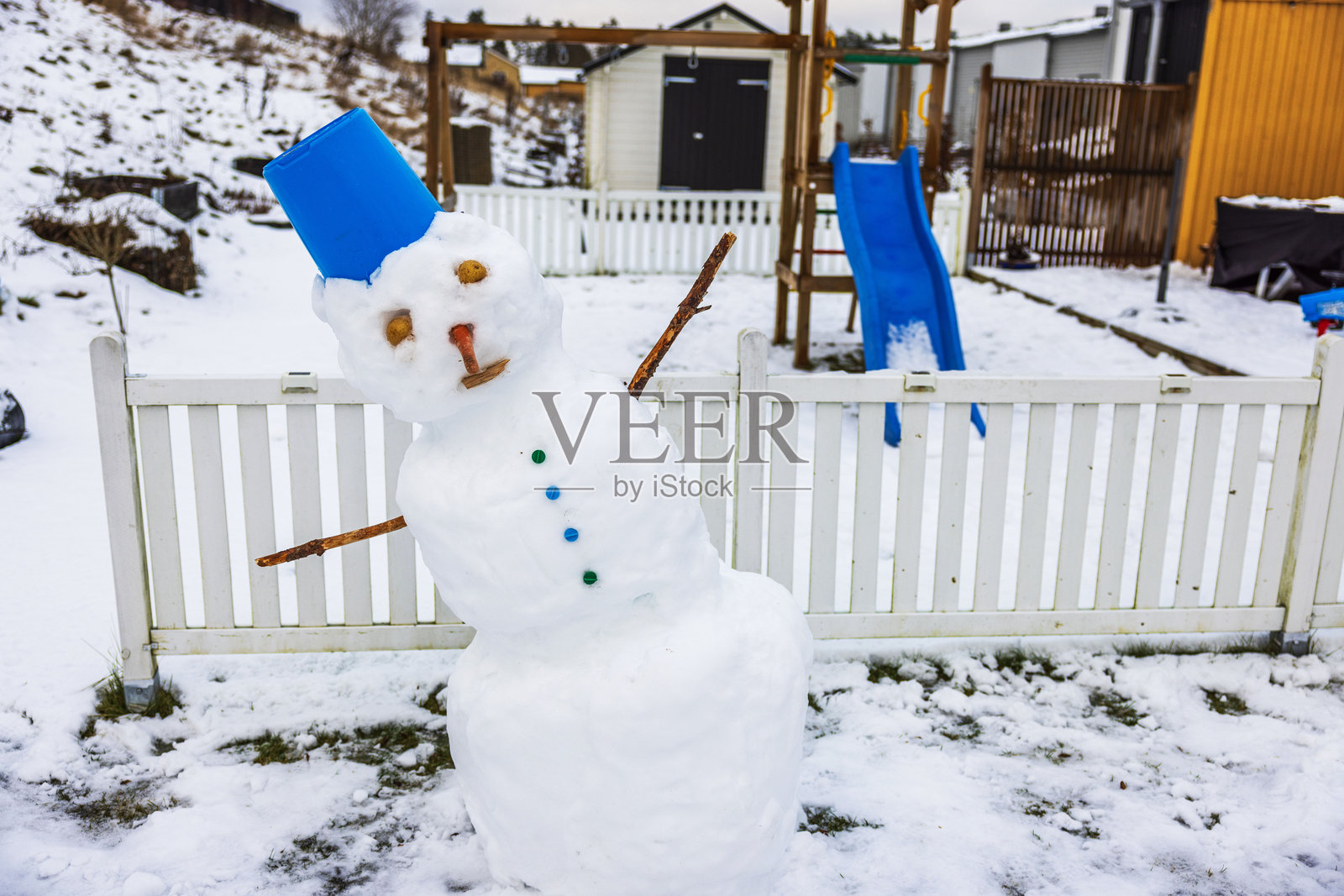 戴蓝色桶的融化雪人照片摄影图片