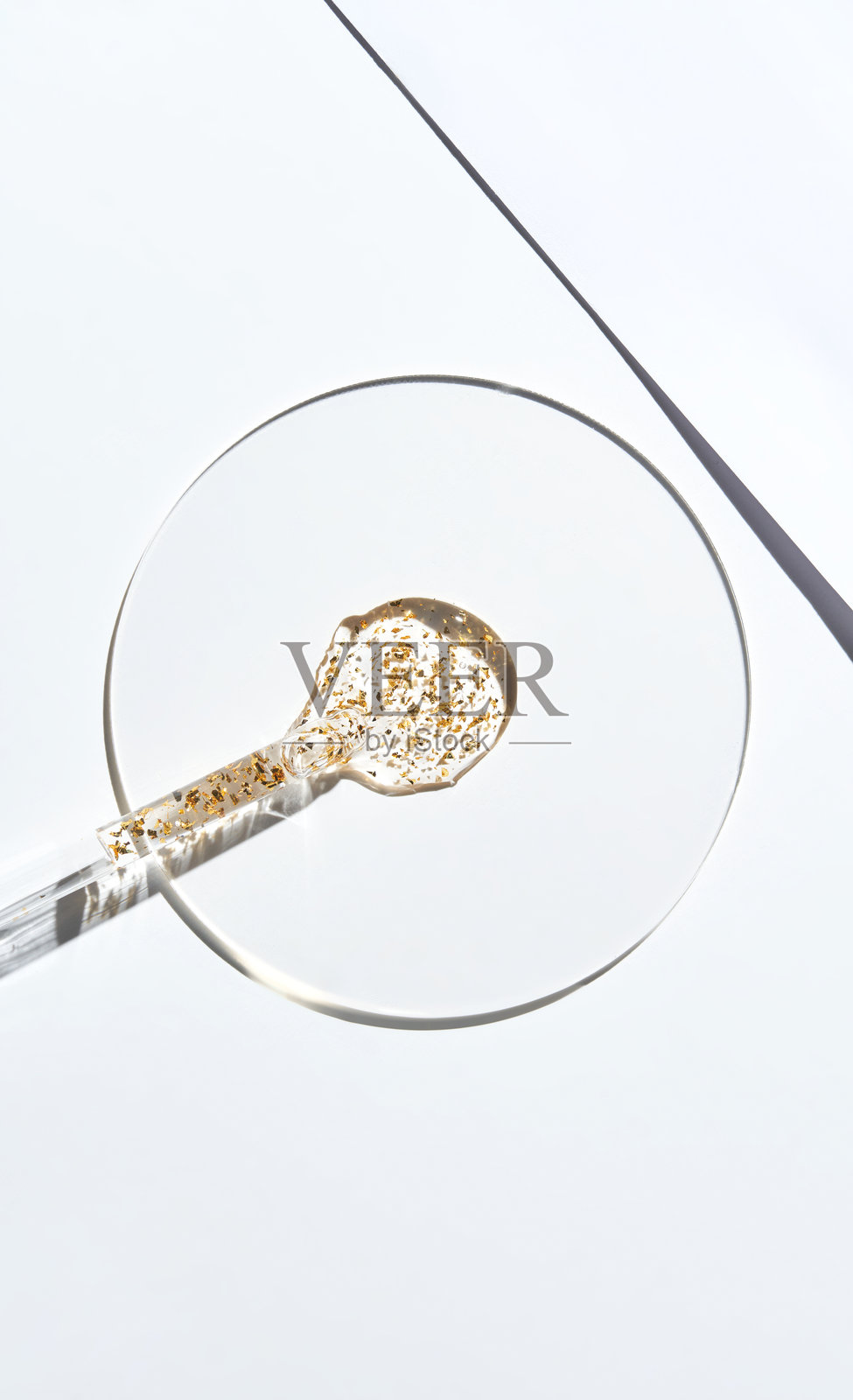 透明的培养皿中含有血清样本和金颗粒，背景为白色照片摄影图片