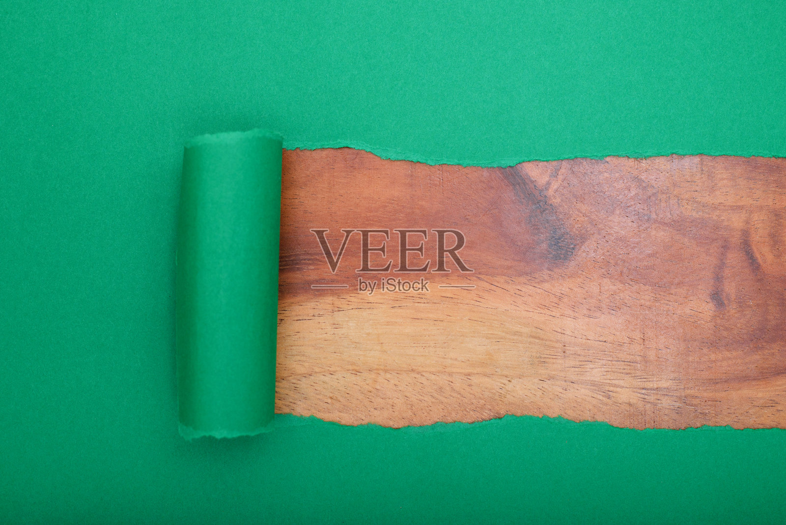 撕裂的绿色纸张揭示出木质背景。留白空间。照片摄影图片