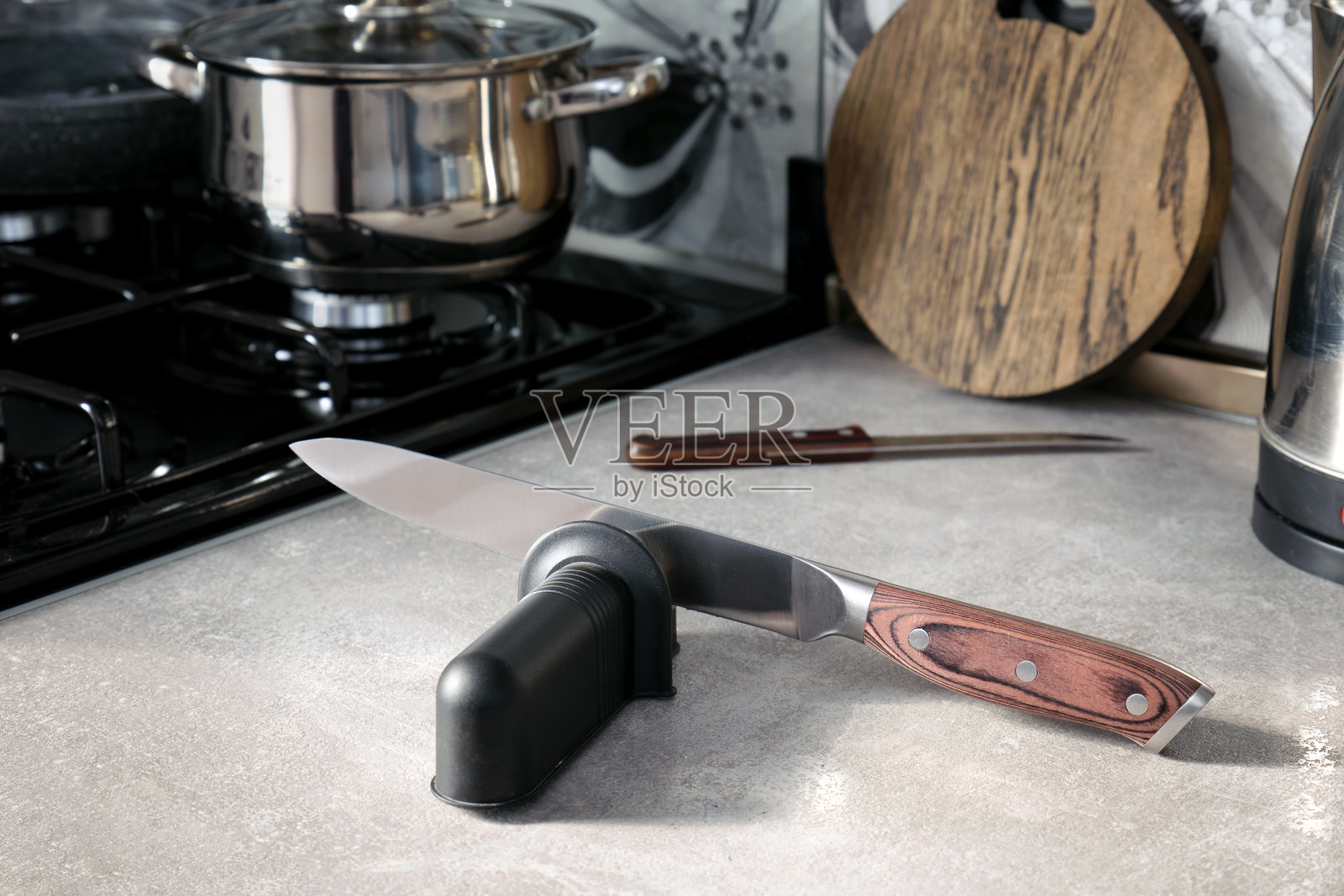 特写一款专用的刀具磨刀器和一把大厨刀放在桌子上。照片摄影图片