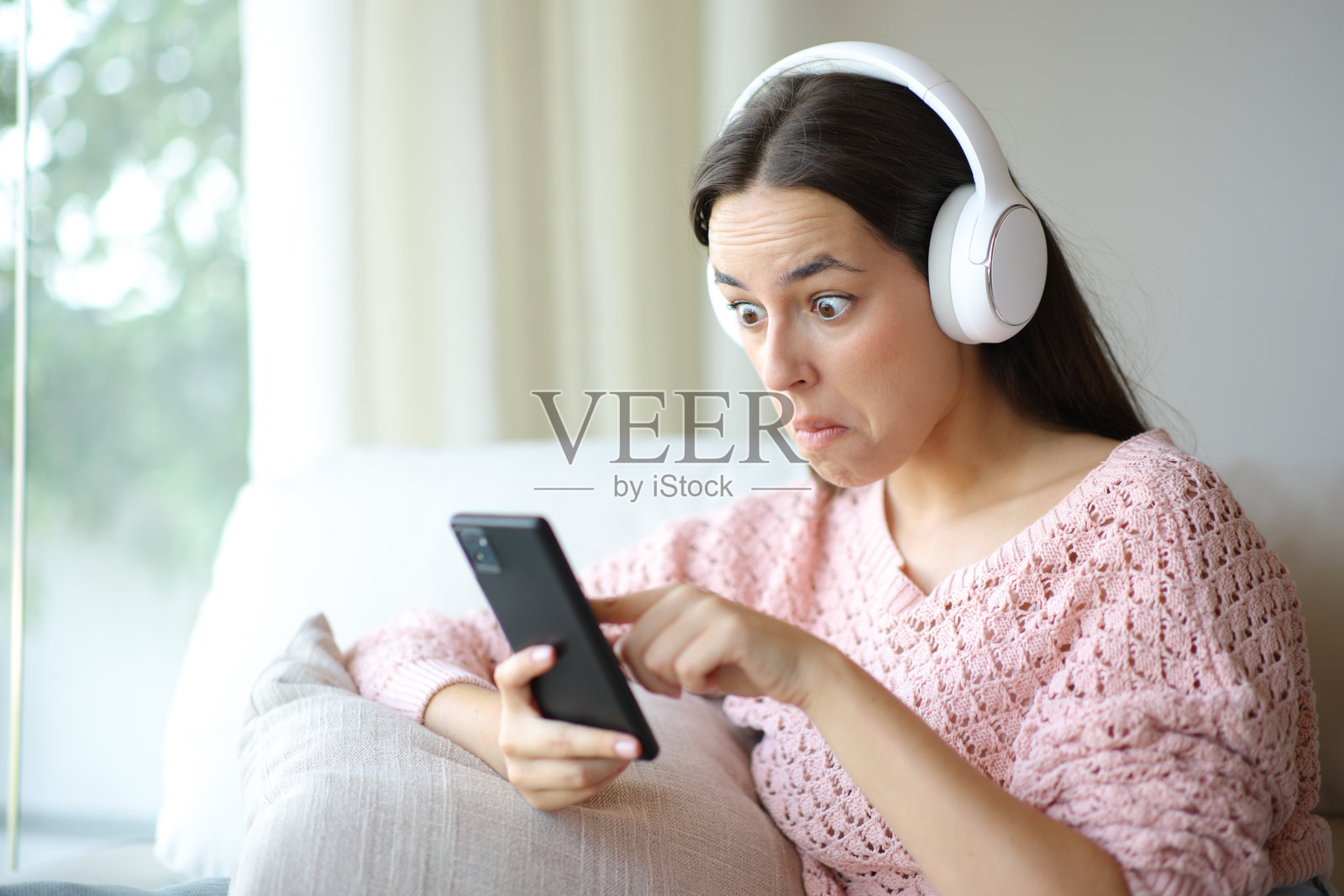 困惑的女性正在用手机和耳机听音频照片摄影图片