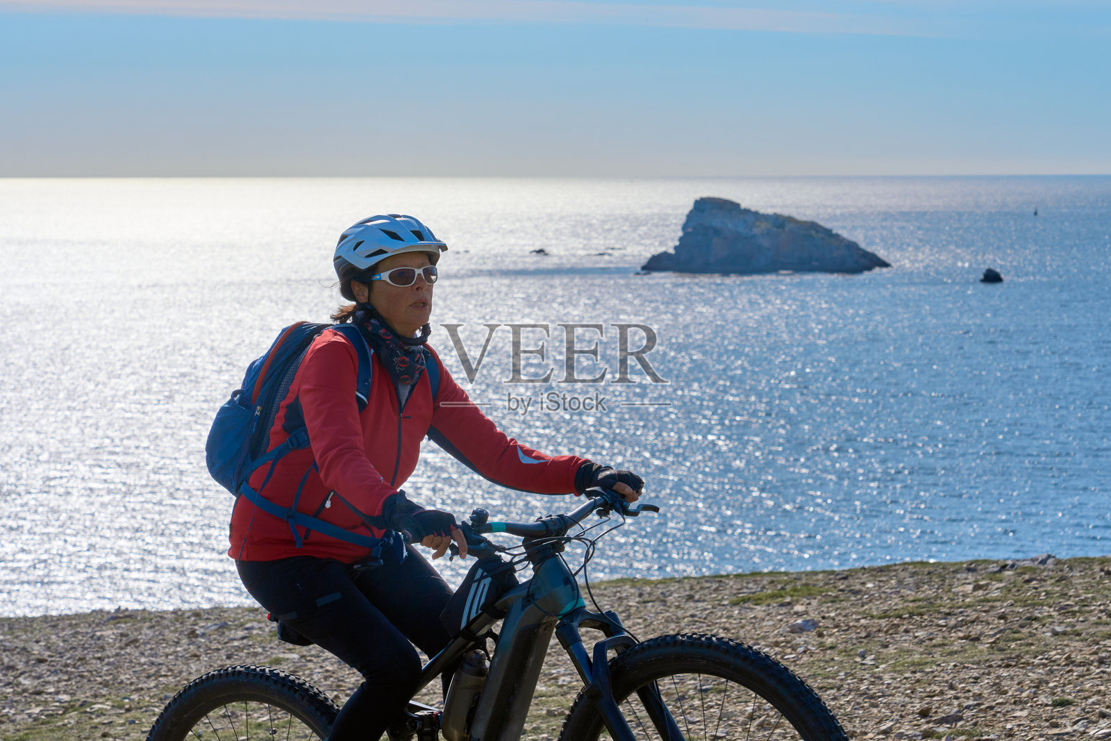 在法国布列塔尼大西洋海岸骑自行车的老年女性照片摄影图片