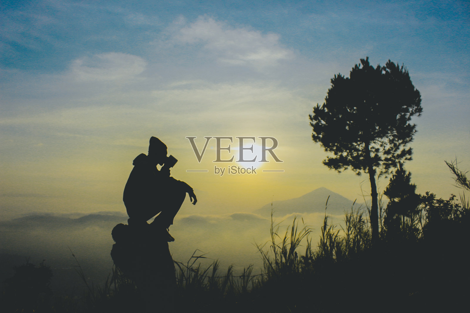 日落时分，坐在岩石上的人影与天空相映成趣照片摄影图片