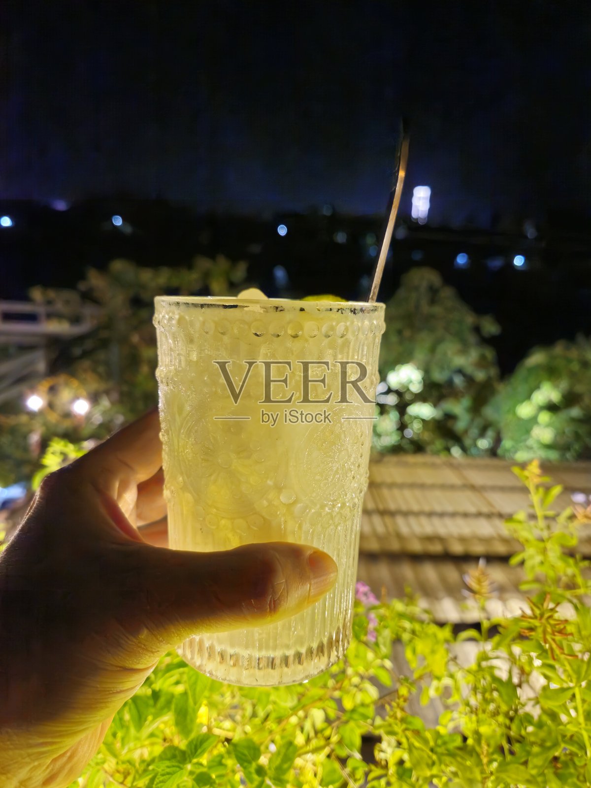 特写镜头：男人的手握着一杯加了柠檬和冰块的越南酸奶。照片摄影图片