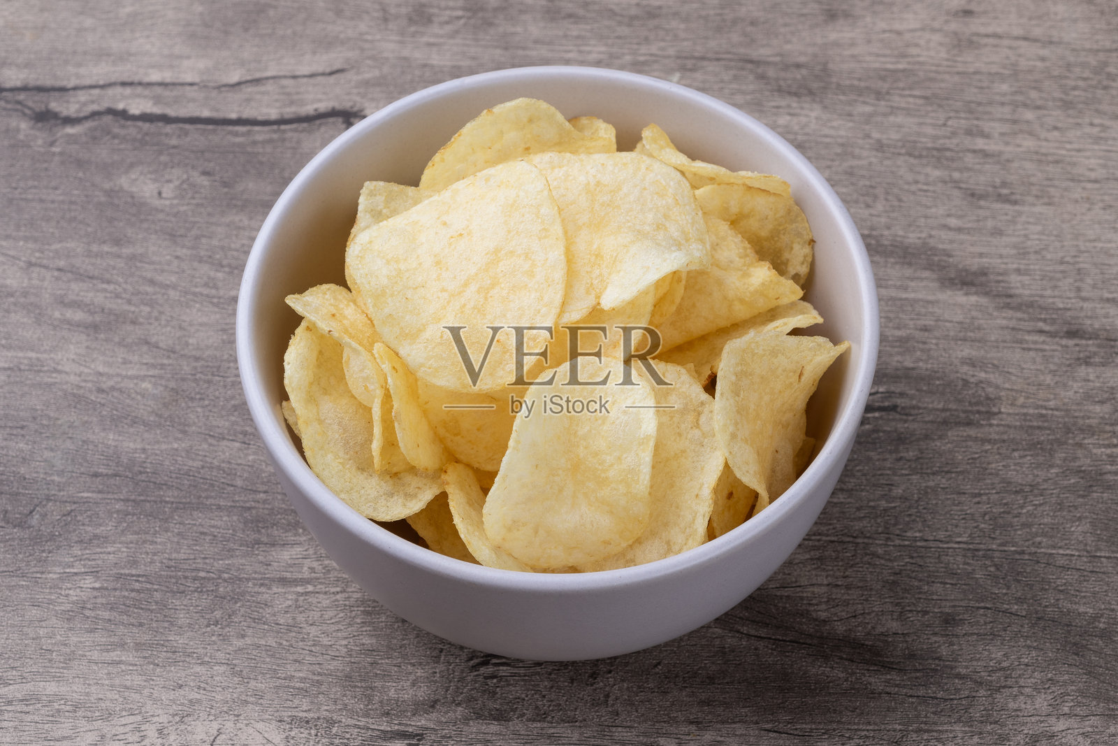 木桌上盛着一碗薯片照片摄影图片