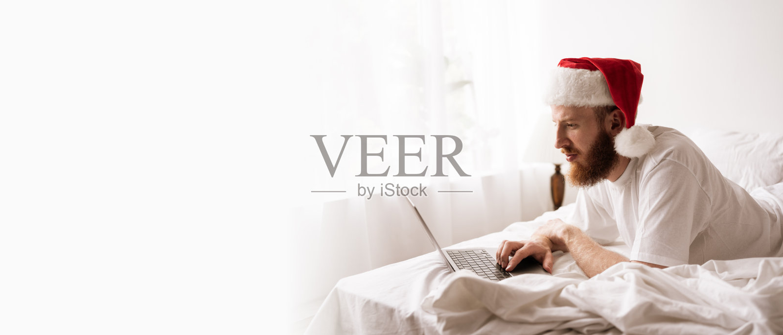 圣诞节早晨，床上的男人正在使用笔记本电脑照片摄影图片