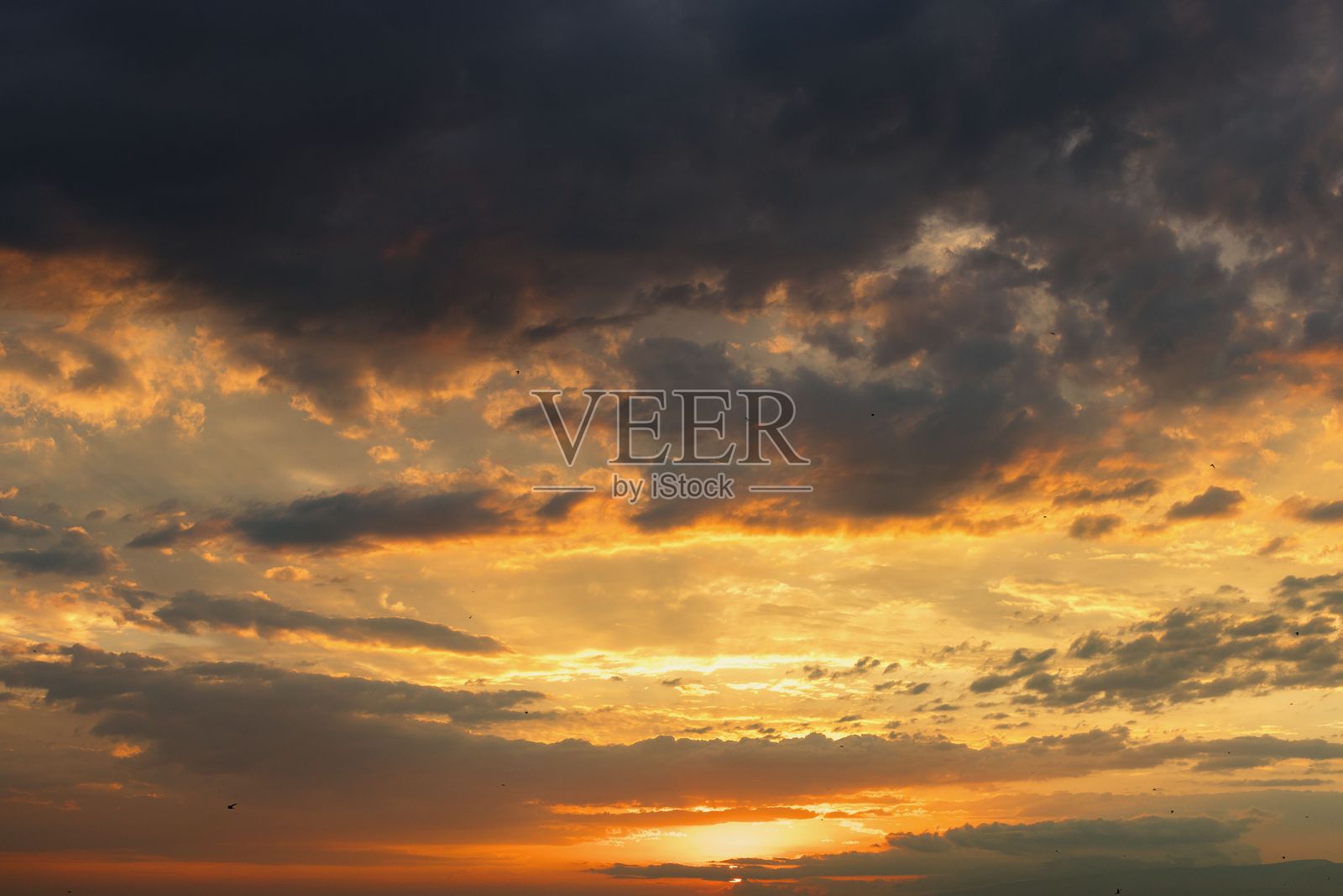 戏剧性的日落天空，明亮的橙色和黄色在乌云下交织照片摄影图片