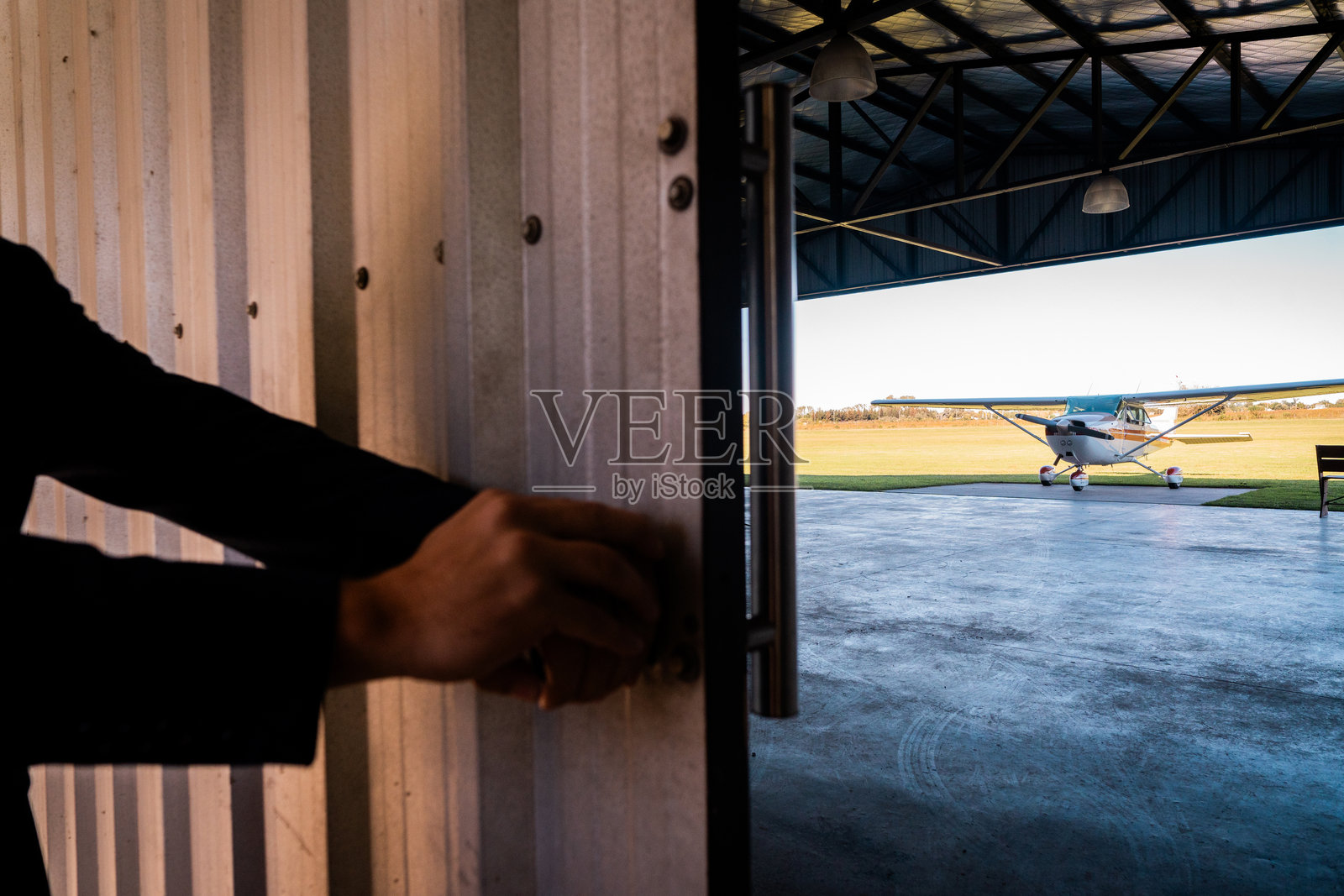 一个人正在打开飞机库的大门的特写镜头照片摄影图片
