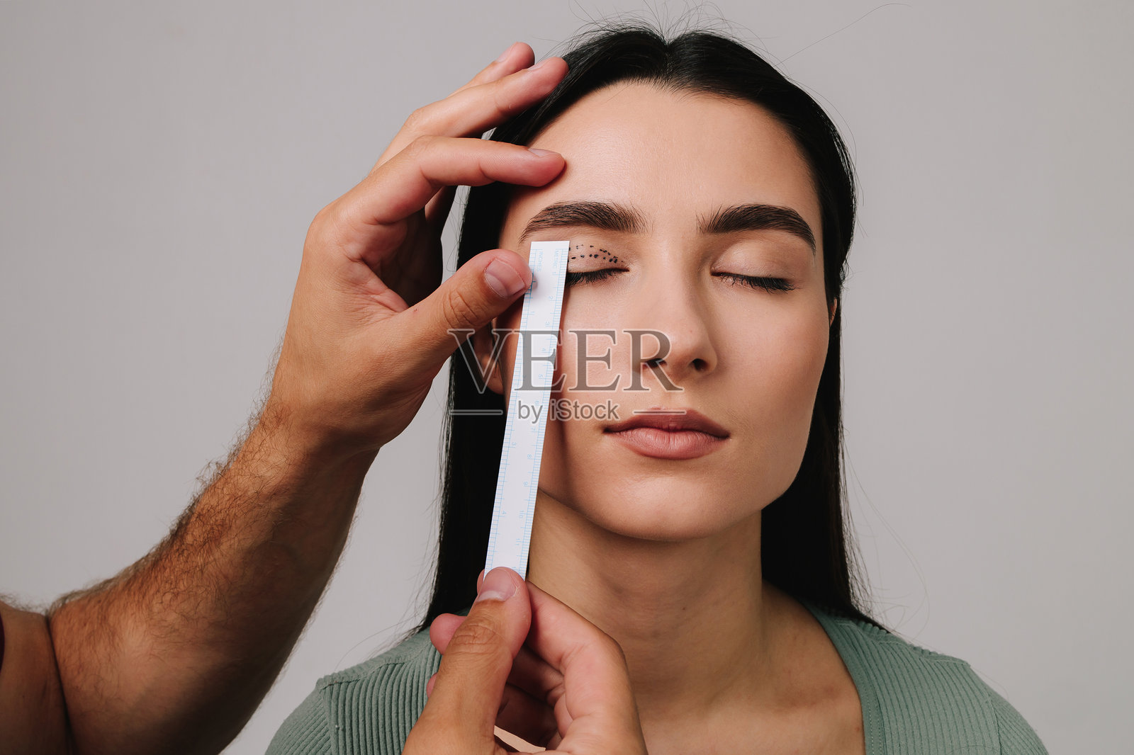 准备进行上睑成形术以矫正下垂的眼睑。整形外科医生正在为患者测量眼部手术距离。照片摄影图片