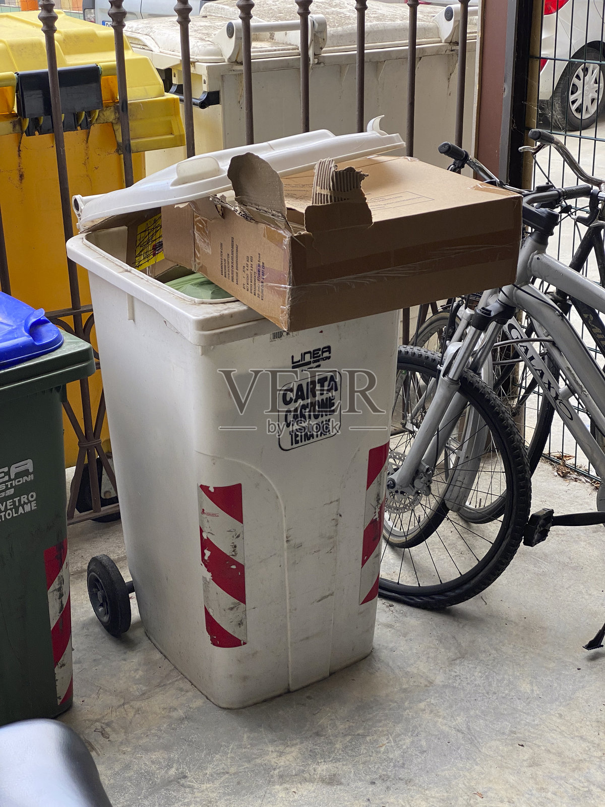 溢出的纸张回收箱，旁边有纸箱和自行车照片摄影图片