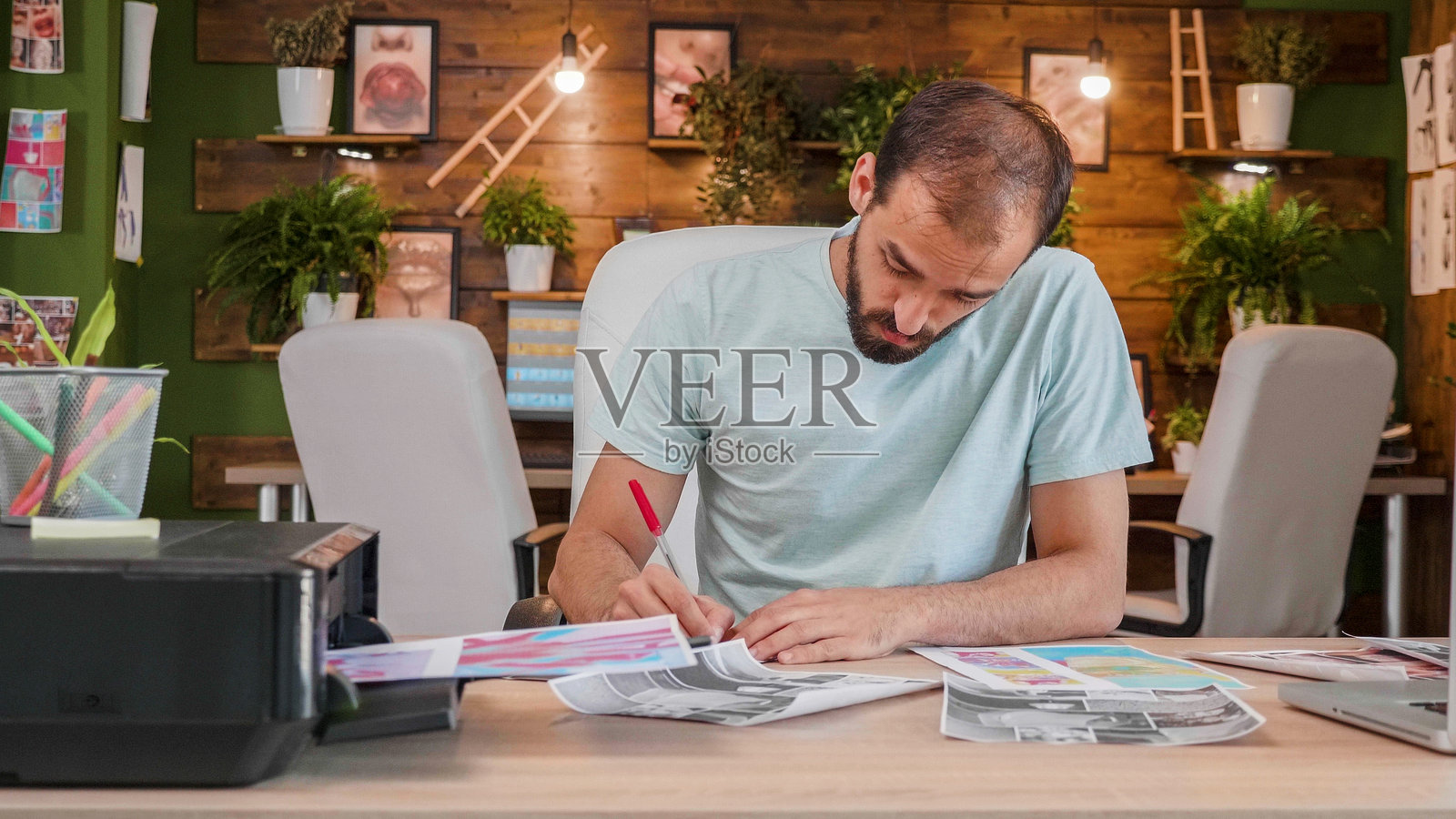 坐在桌子前的设计男孩正在对一些打印的纸张做笔记。照片摄影图片
