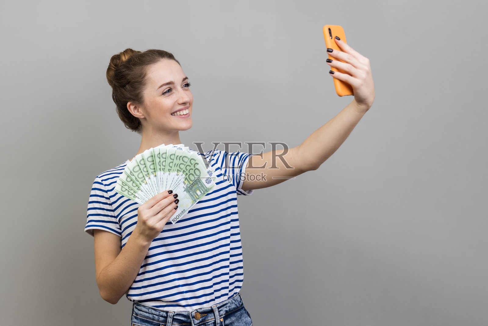 女性在直播中向粉丝展示欧元钞票，炫耀自己的薪水。照片摄影图片