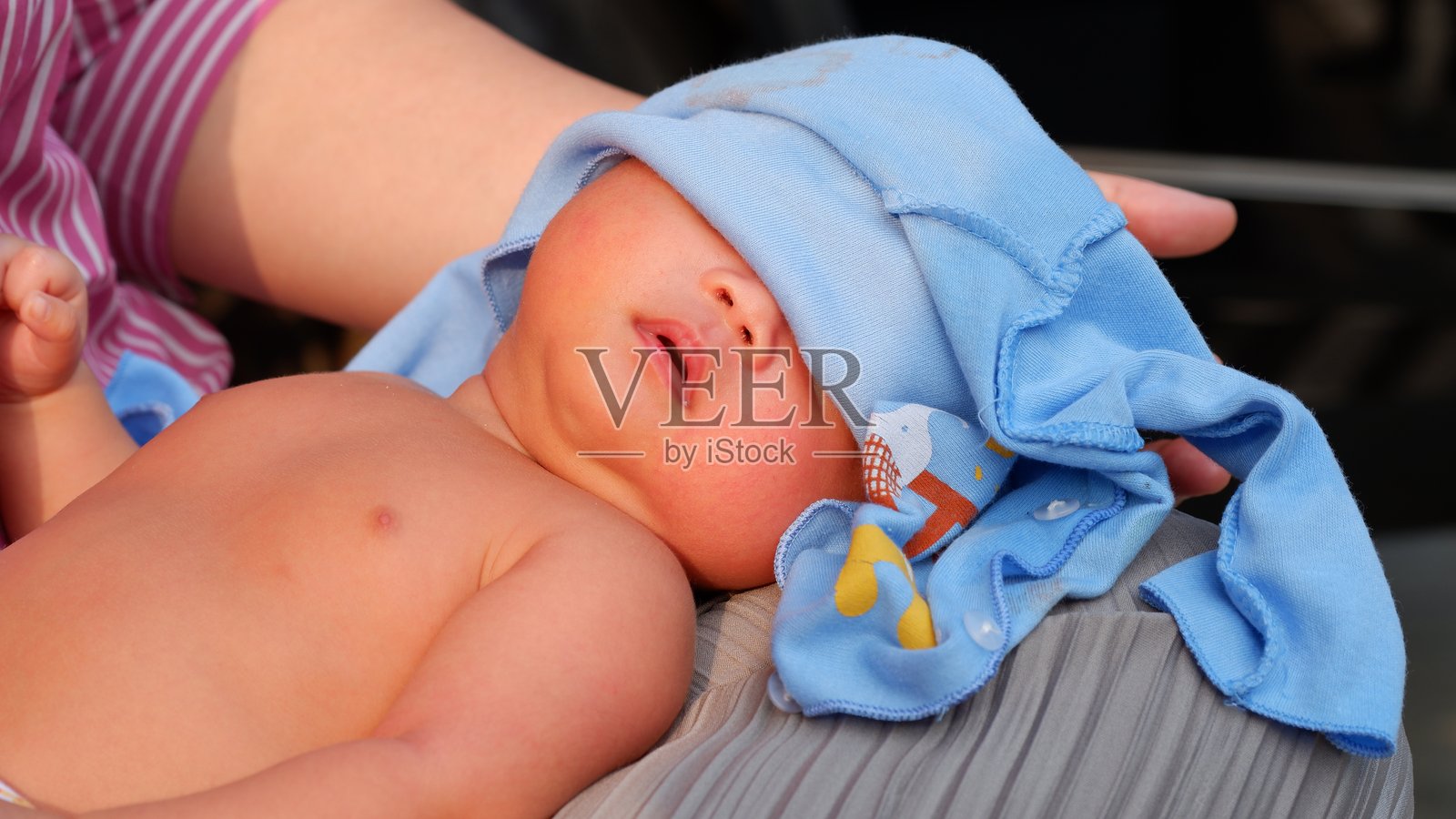 一个新生儿在早晨晒太阳时用衣物遮住了眼睛。照片摄影图片