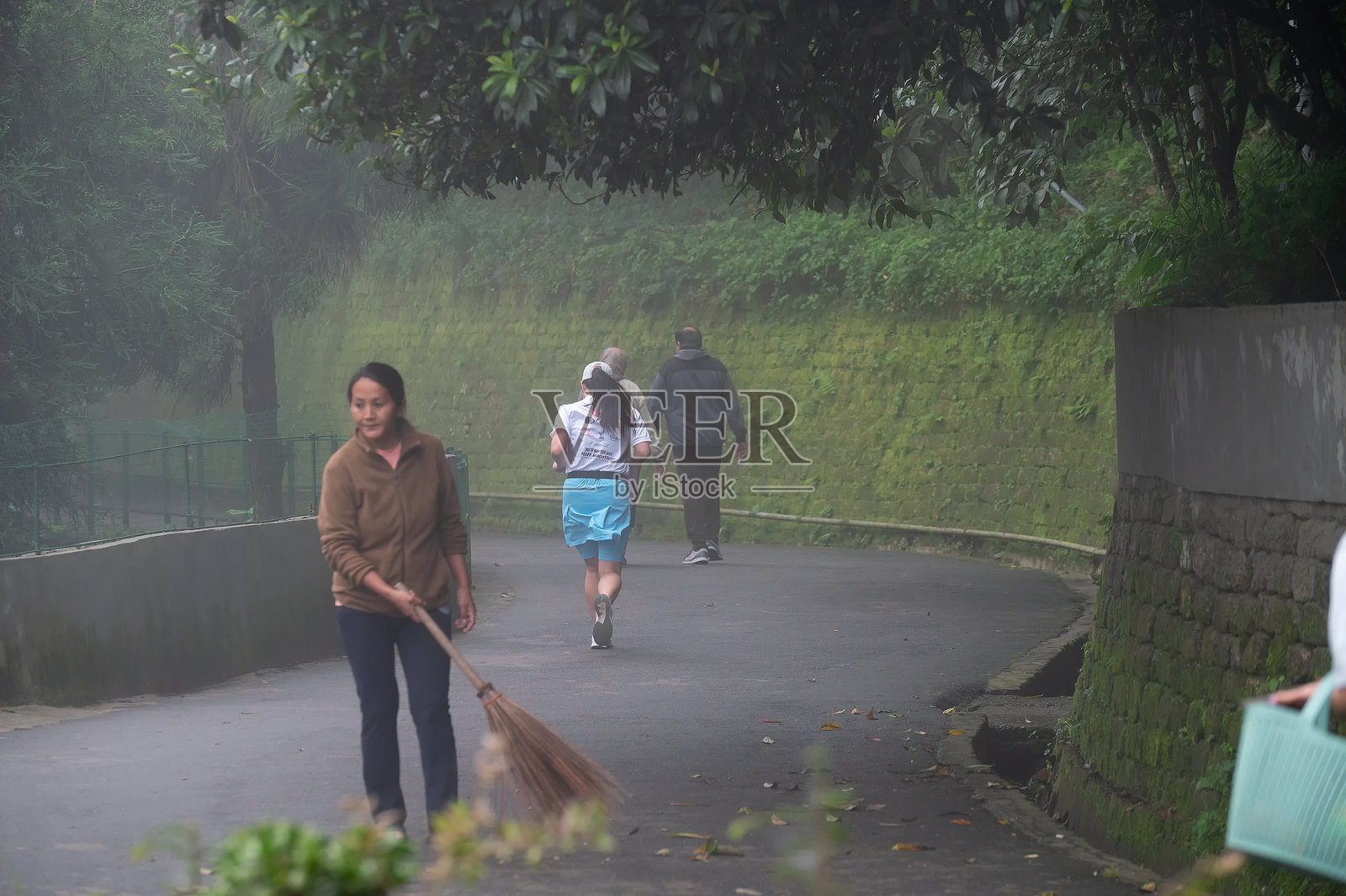 健康意识强的年轻女性在达尔杰林的雾霭清晨跑步。穿着运动服，展现年轻的喜马拉雅生活方式。照片摄影图片