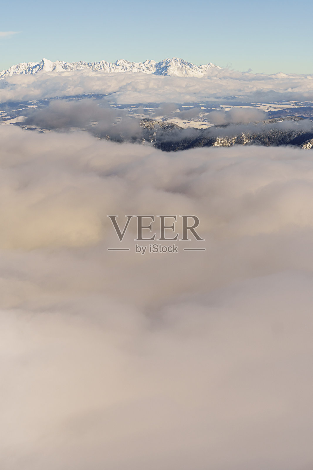 冬季从高处俯瞰被云雾覆盖的山谷和雪-covered高塔特拉山脉照片摄影图片