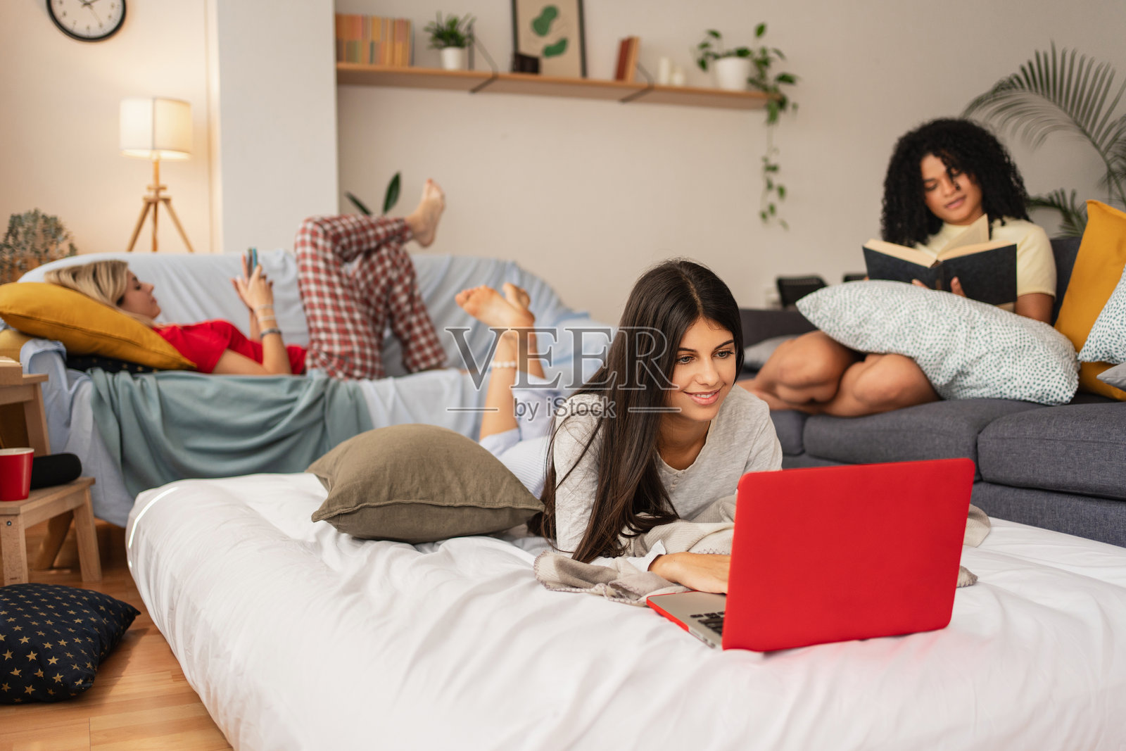 周末穿着睡衣的室友女孩们在床上轻松学习和工作照片摄影图片