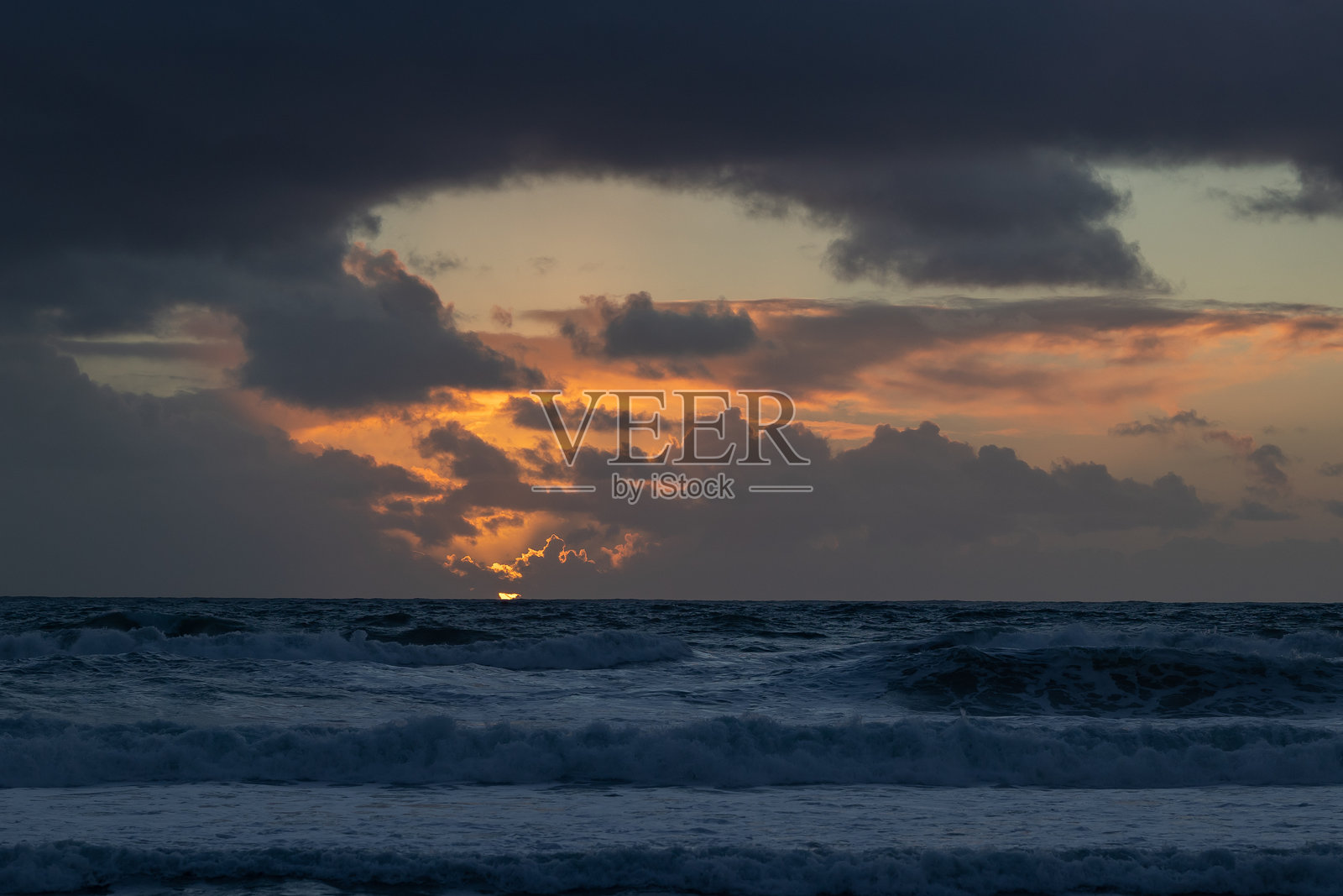 多云的明亮日落映照在蓝色海面上照片摄影图片