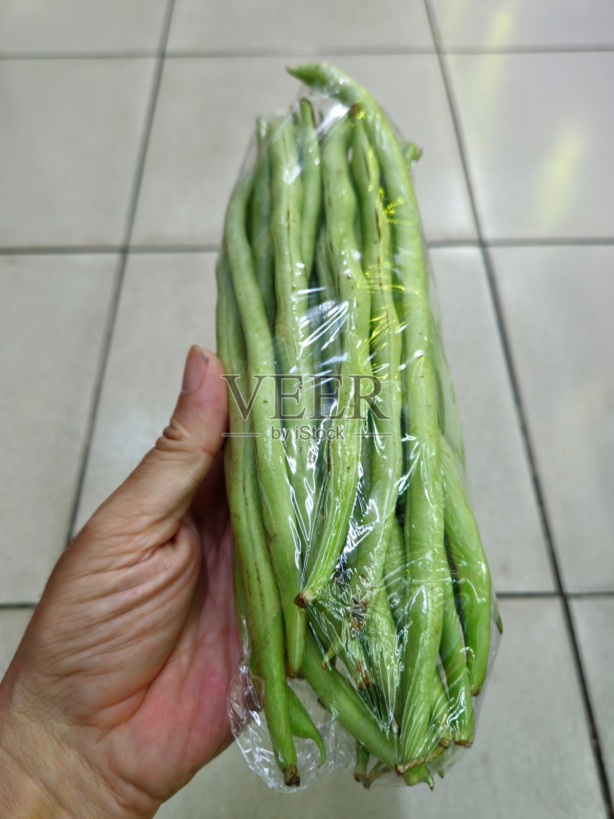 越南超市中，男子手中握着包裹在塑料袋里的绿豆特写。绿豆独立展示。照片摄影图片