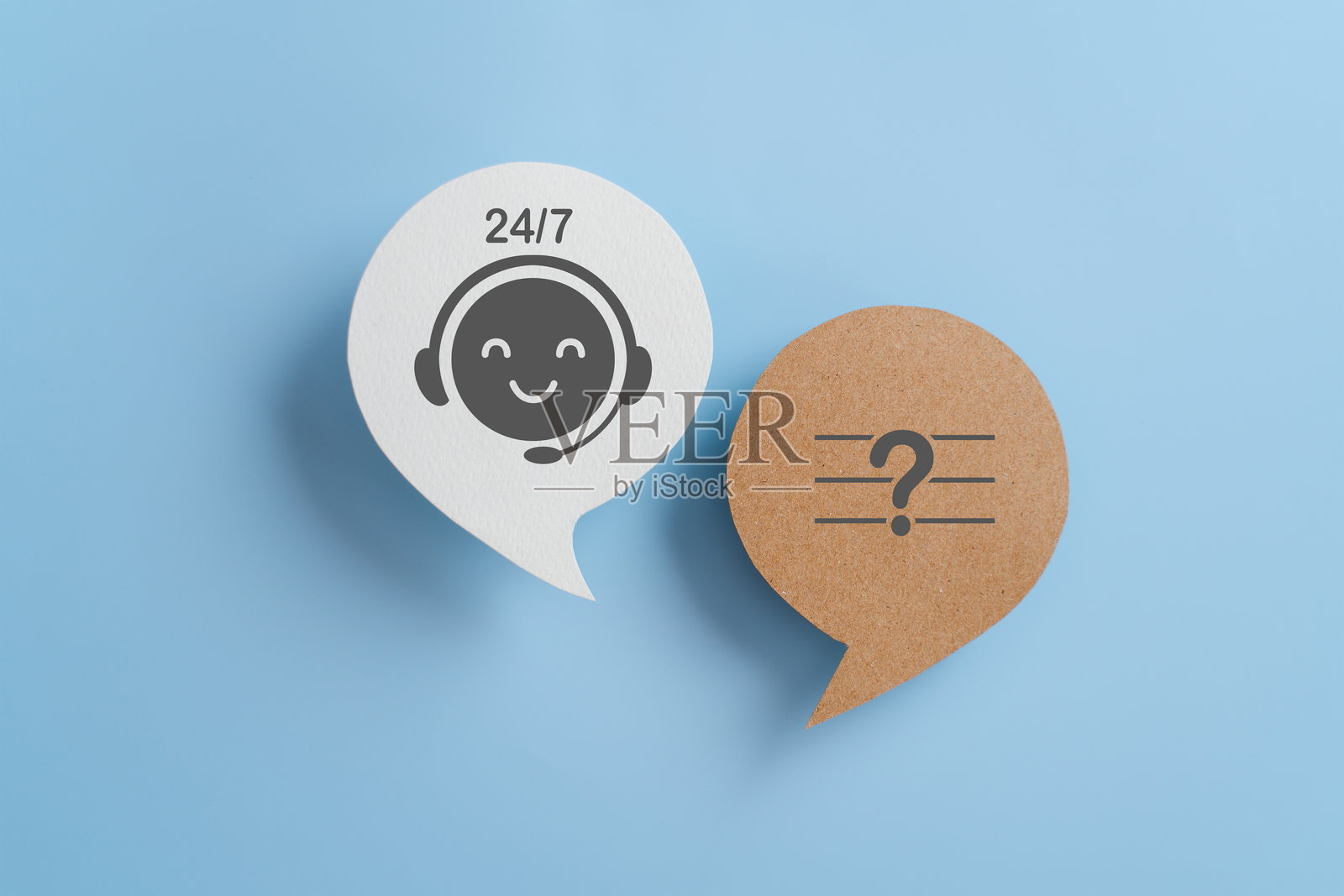 24小时7天全天候客户服务概念。白色真实对话气泡纸上带微笑的脸和棕色背景上的问号，蓝色背景。照片摄影图片