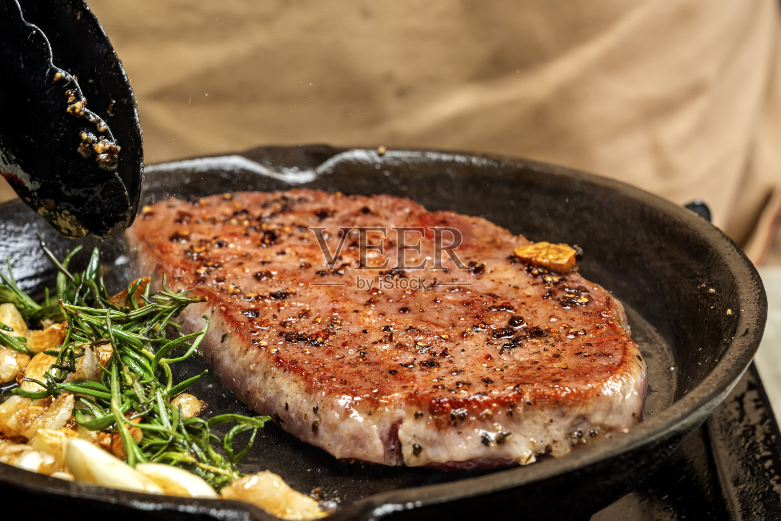 一个人在炉子上的平底锅里烹饪皮卡尼亚牛排照片摄影图片