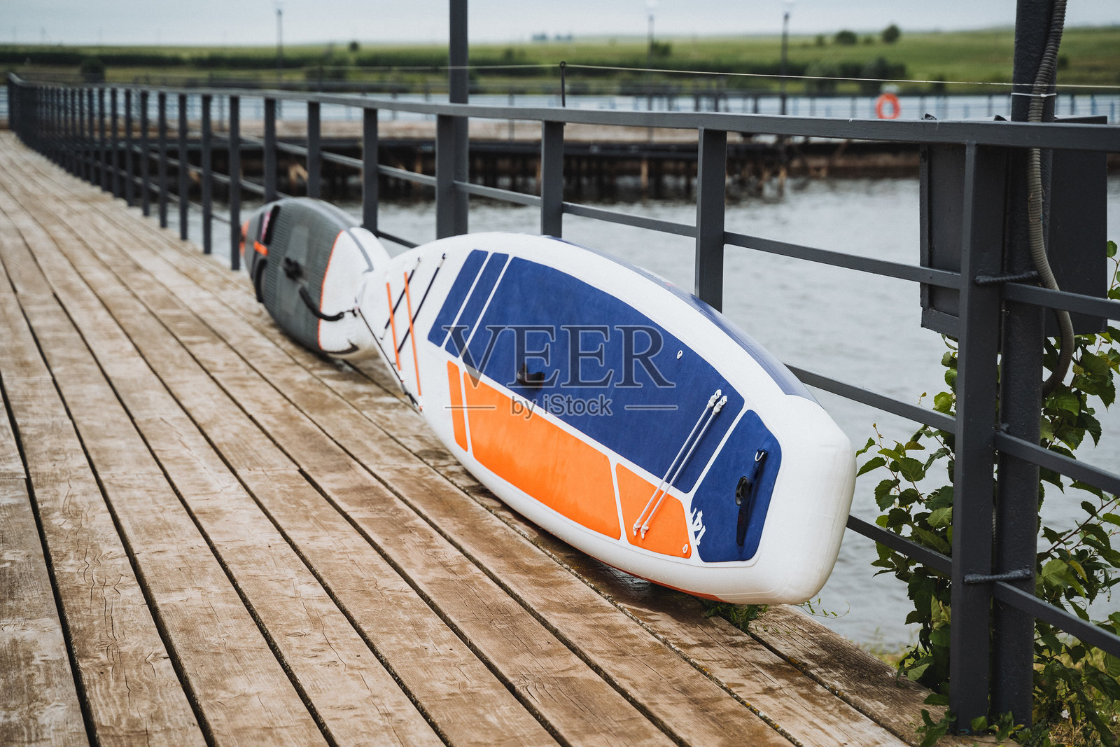 一块冲浪板静静地躺在水边的木栈道上，营造出一个宁静的地方，可以欣赏海洋和波浪。这座栈道非常适合欣赏冲浪板的美丽和周围的自然风光。照片摄影图片