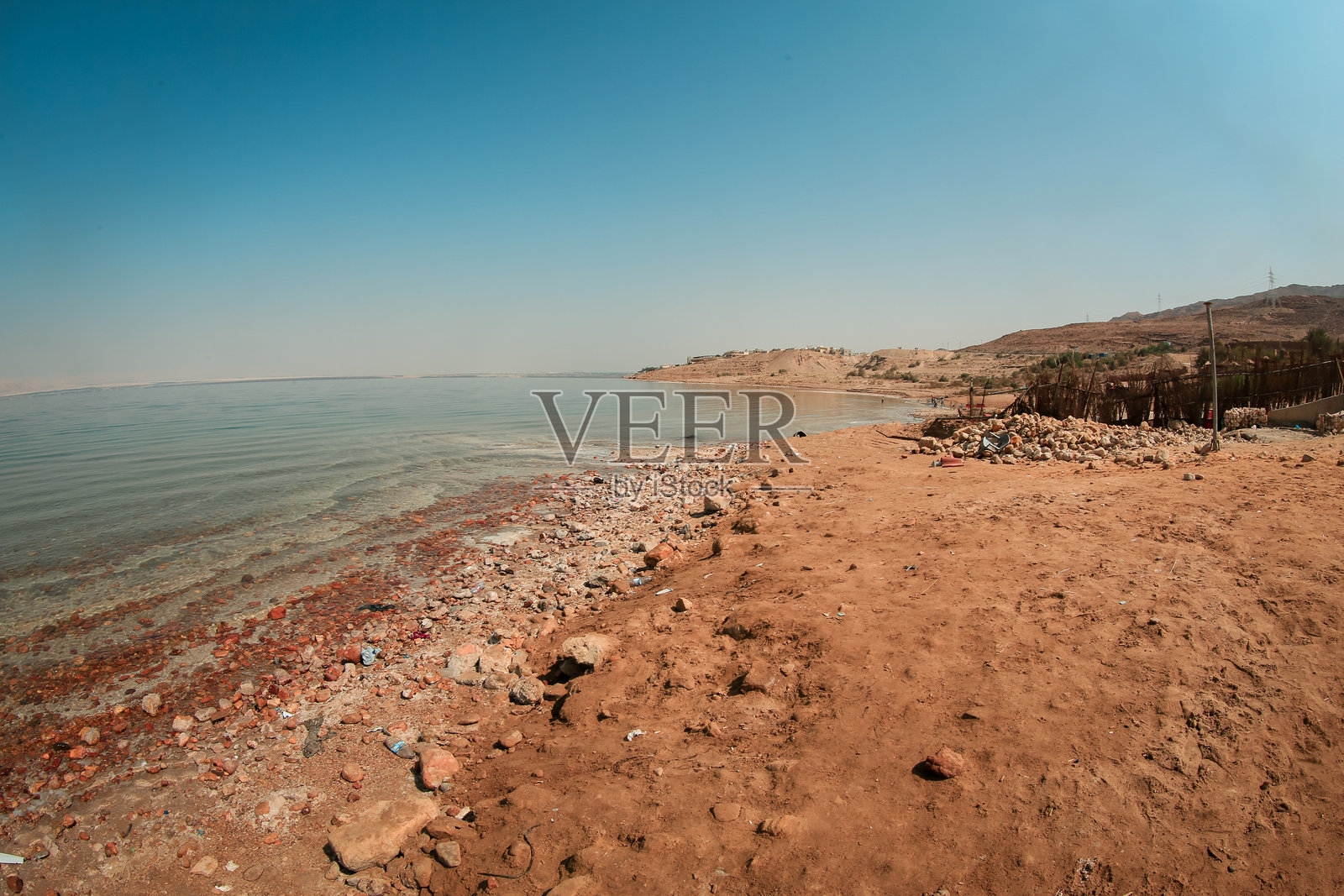 约旦死海的宁静风光，展现了清澈蓝天下的海岸线和干旱地形照片摄影图片