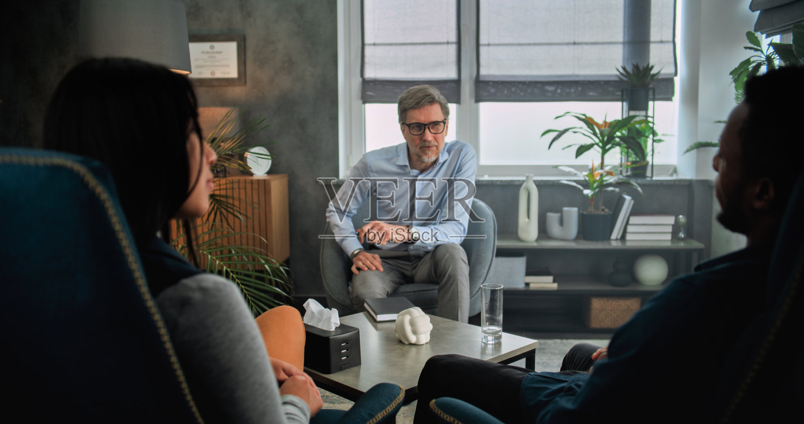 成熟的心理治疗师与年轻家庭交谈，提供夫妻治疗。照片摄影图片