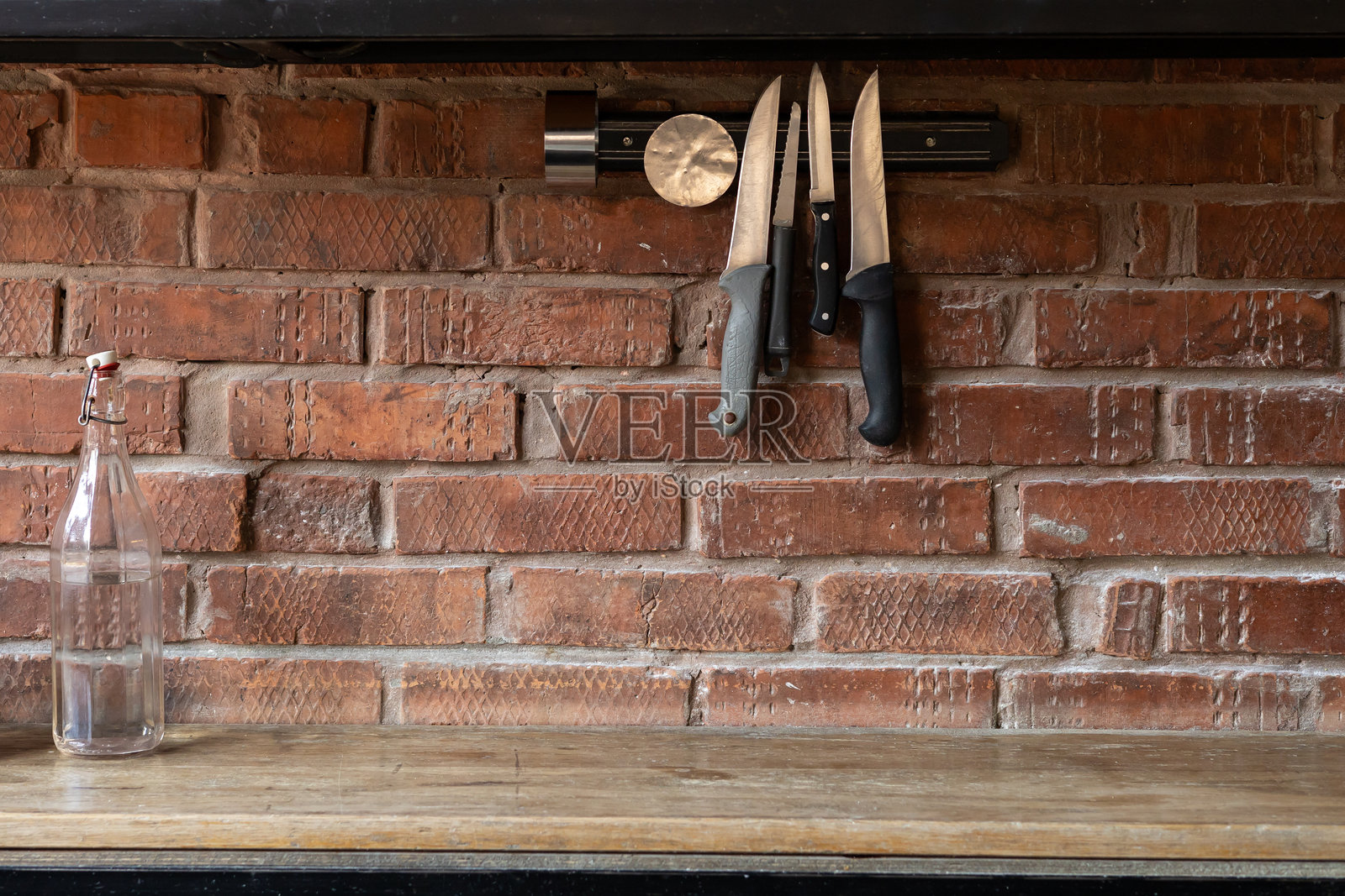 木架上展示的刀具，背景是乡村风格的砖墙和一个玻璃瓶照片摄影图片