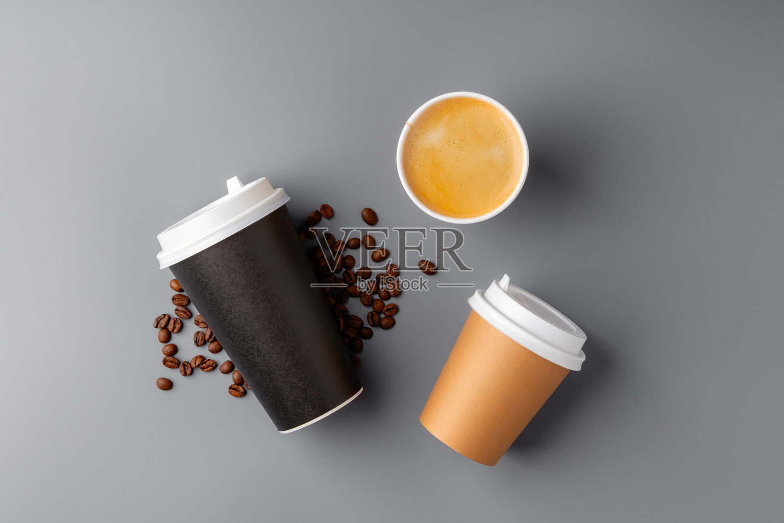 一只黑色咖啡杯周围环绕着烘焙咖啡豆，放在灰色表面上照片摄影图片