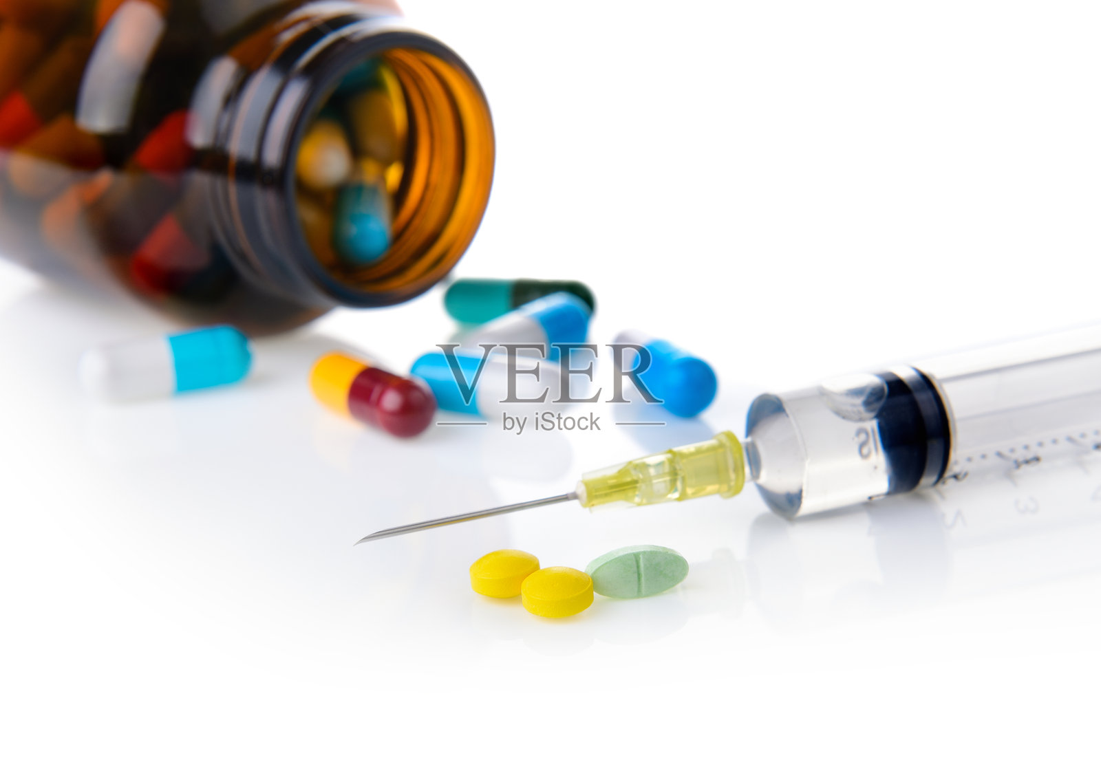 白色背景上带有药丸和瓶子的注射器特写照片摄影图片
