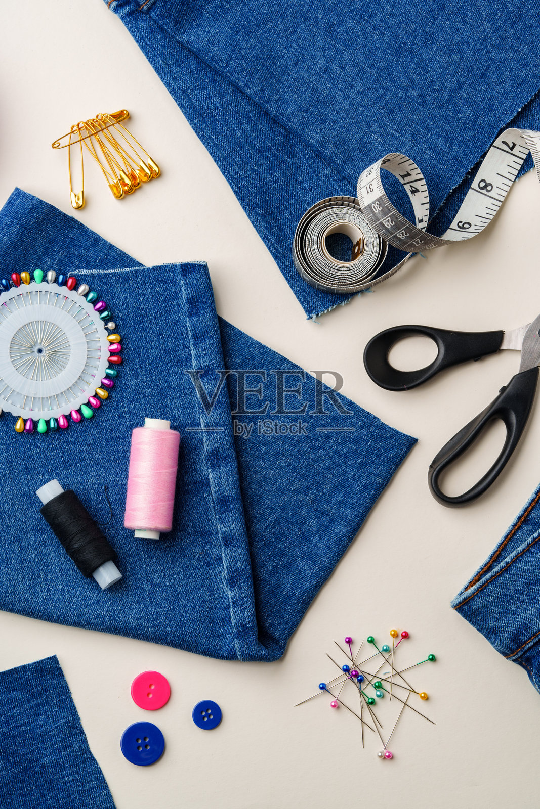 明亮环境中，缝纫用品和牛仔布整齐地摆放在服装改造的工作台上照片摄影图片