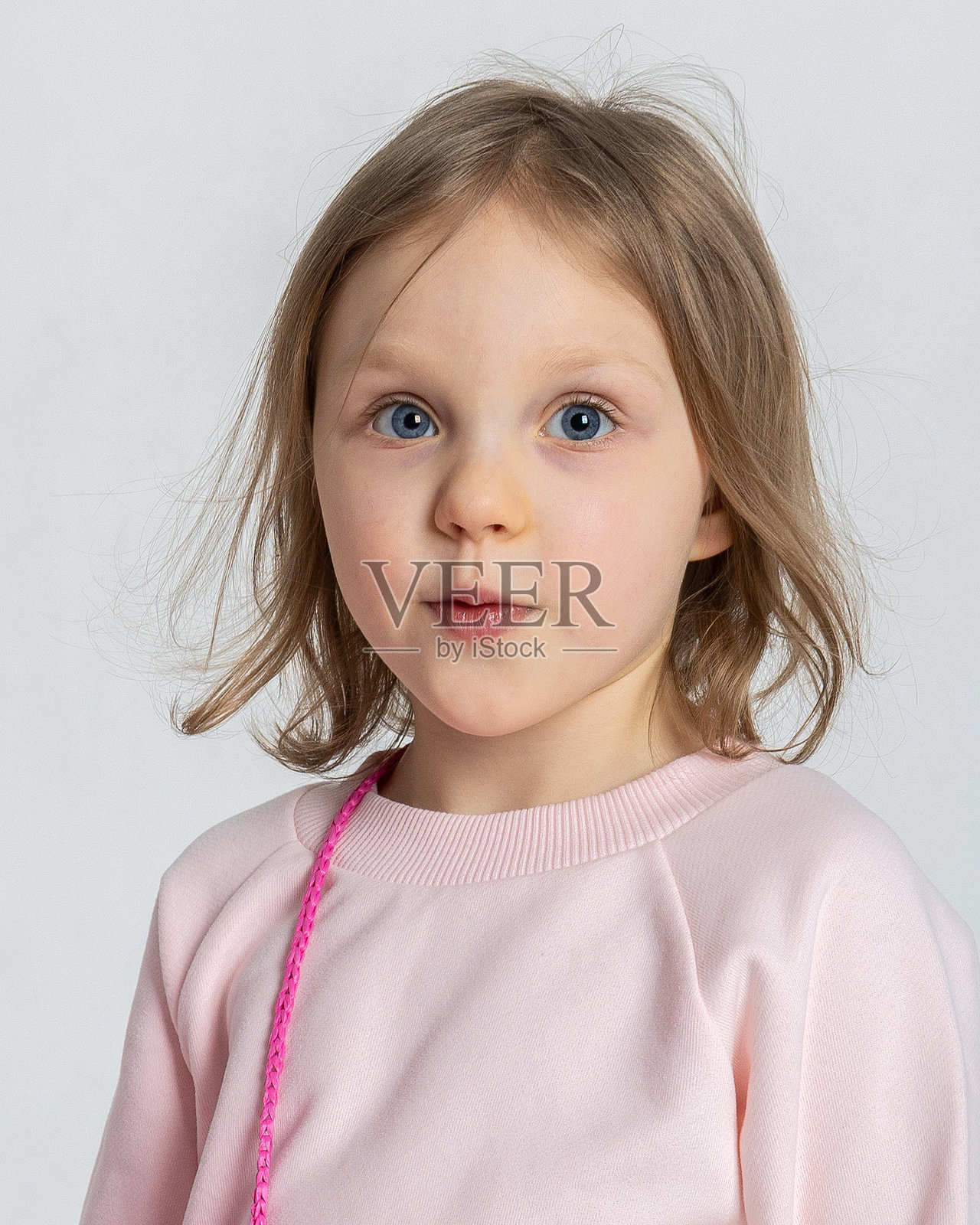 可爱的小女孩肖像。漂亮的微笑孩子在明亮背景的摄影棚中。照片摄影图片