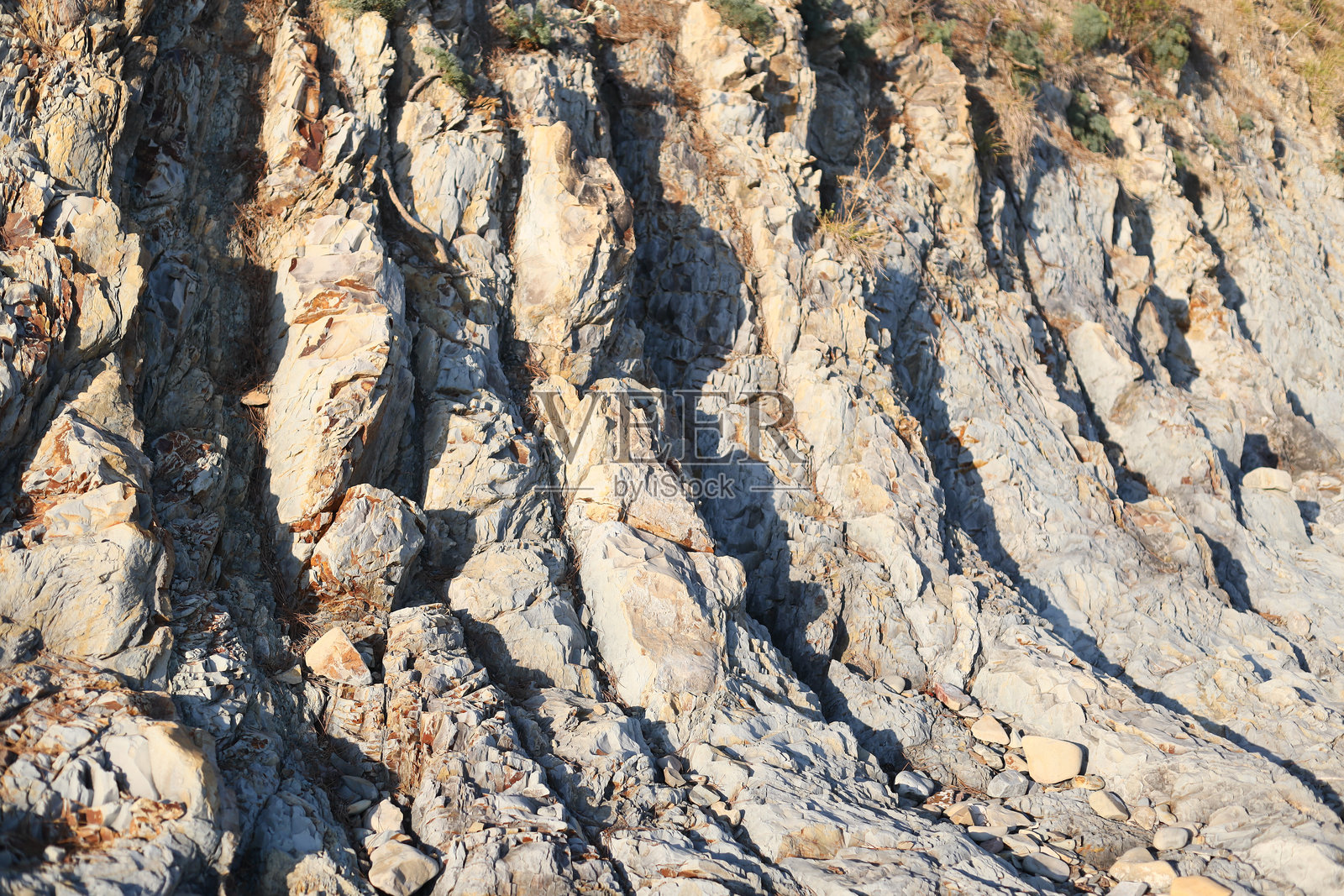 一个人在岩石海岸上骑着冲浪板，背景是波涛汹涌的海浪。照片摄影图片