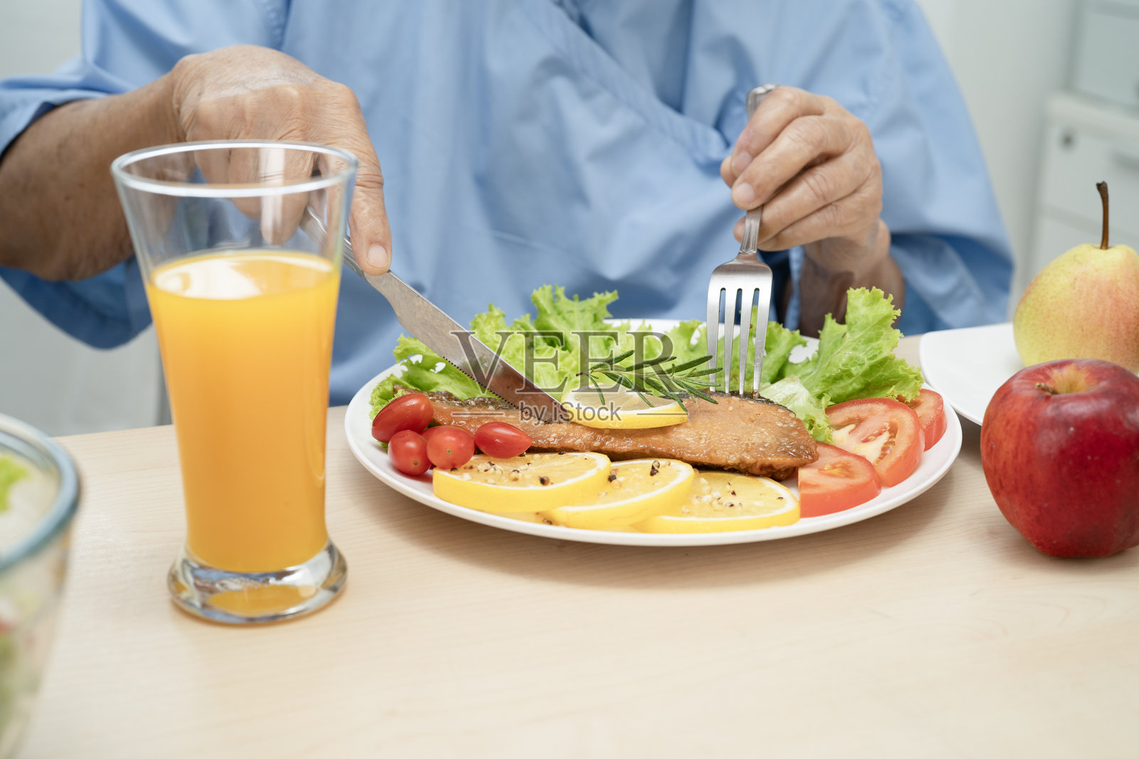 亚洲老年女性患者在医院吃三文鱼排和蔬菜沙拉，享受健康饮食。照片摄影图片