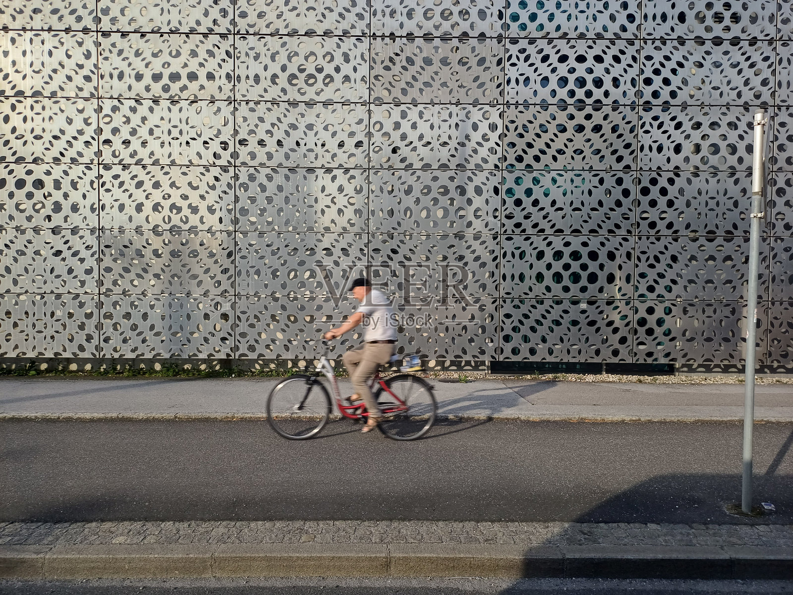 一名男子在奥地利萨尔茨堡市的街道上骑自行车,夕阳西下。照片摄影图片