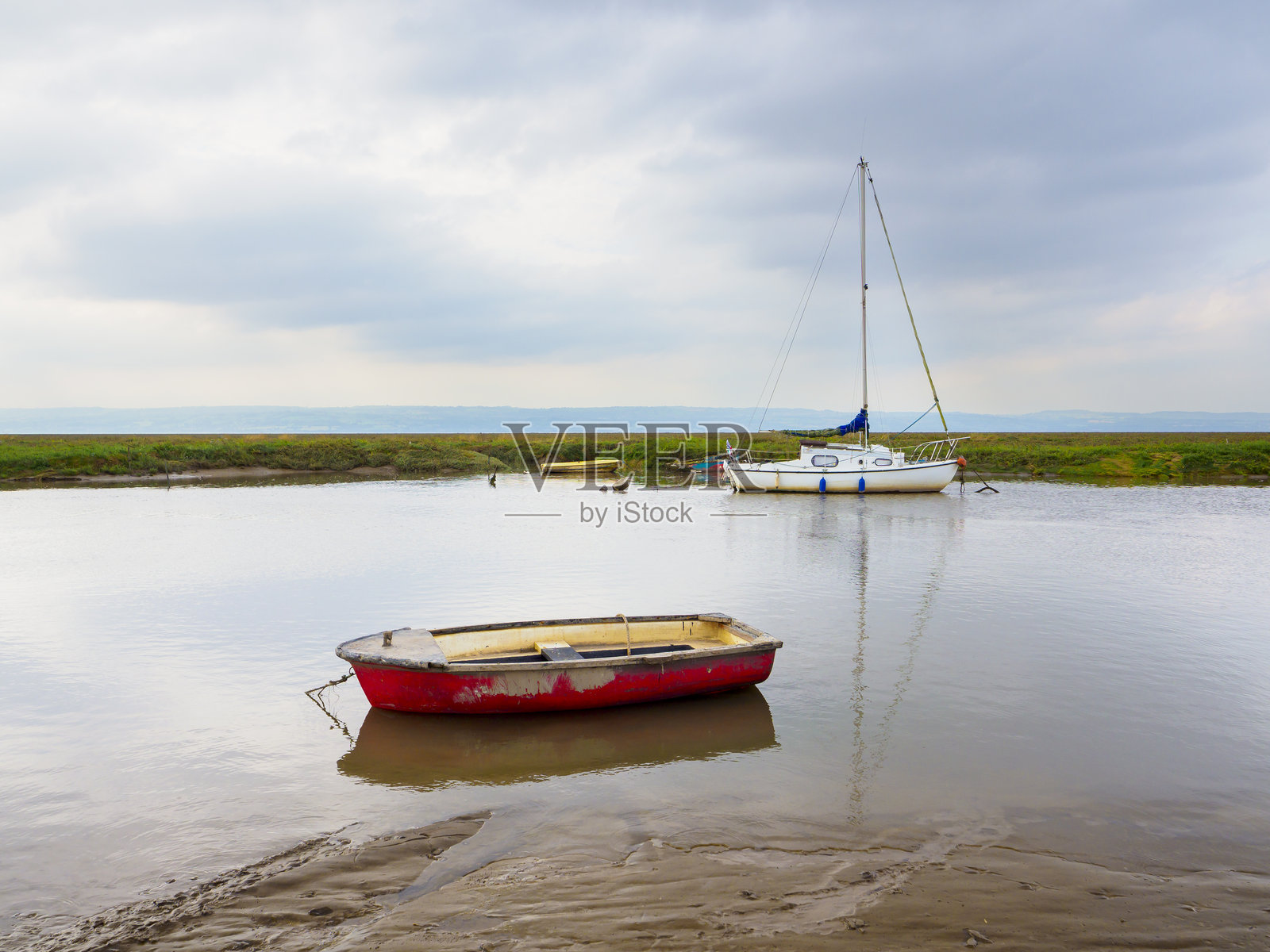 英国威勒尔的赫斯沃尔。两艘船在宁静的多云河畔环境中停泊。照片摄影图片