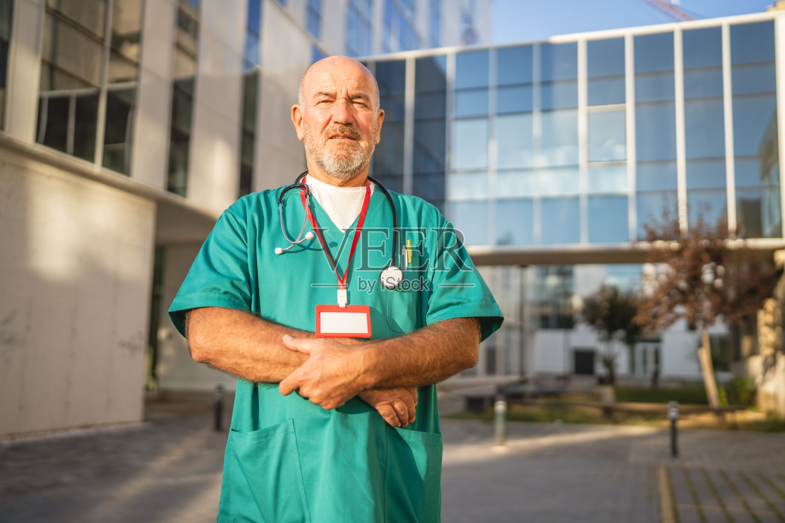 成熟的老年男性医生站在医院前面的人像照片摄影图片