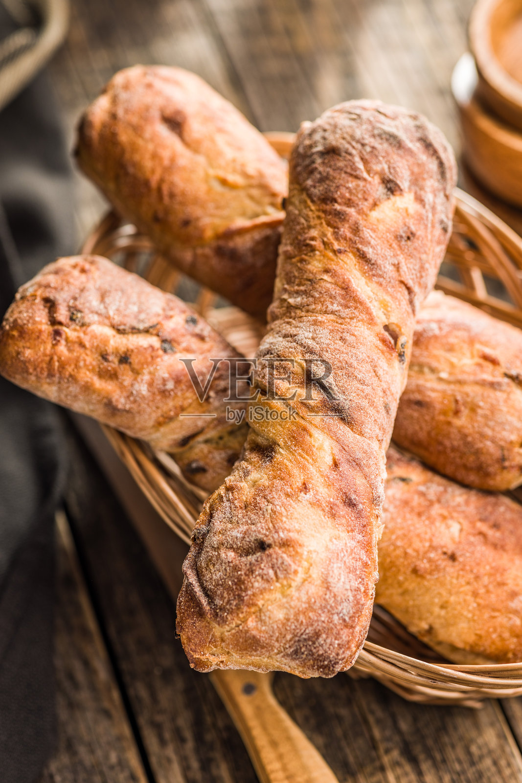 篮子里的酥脆乡村法棍放在木桌上。照片摄影图片