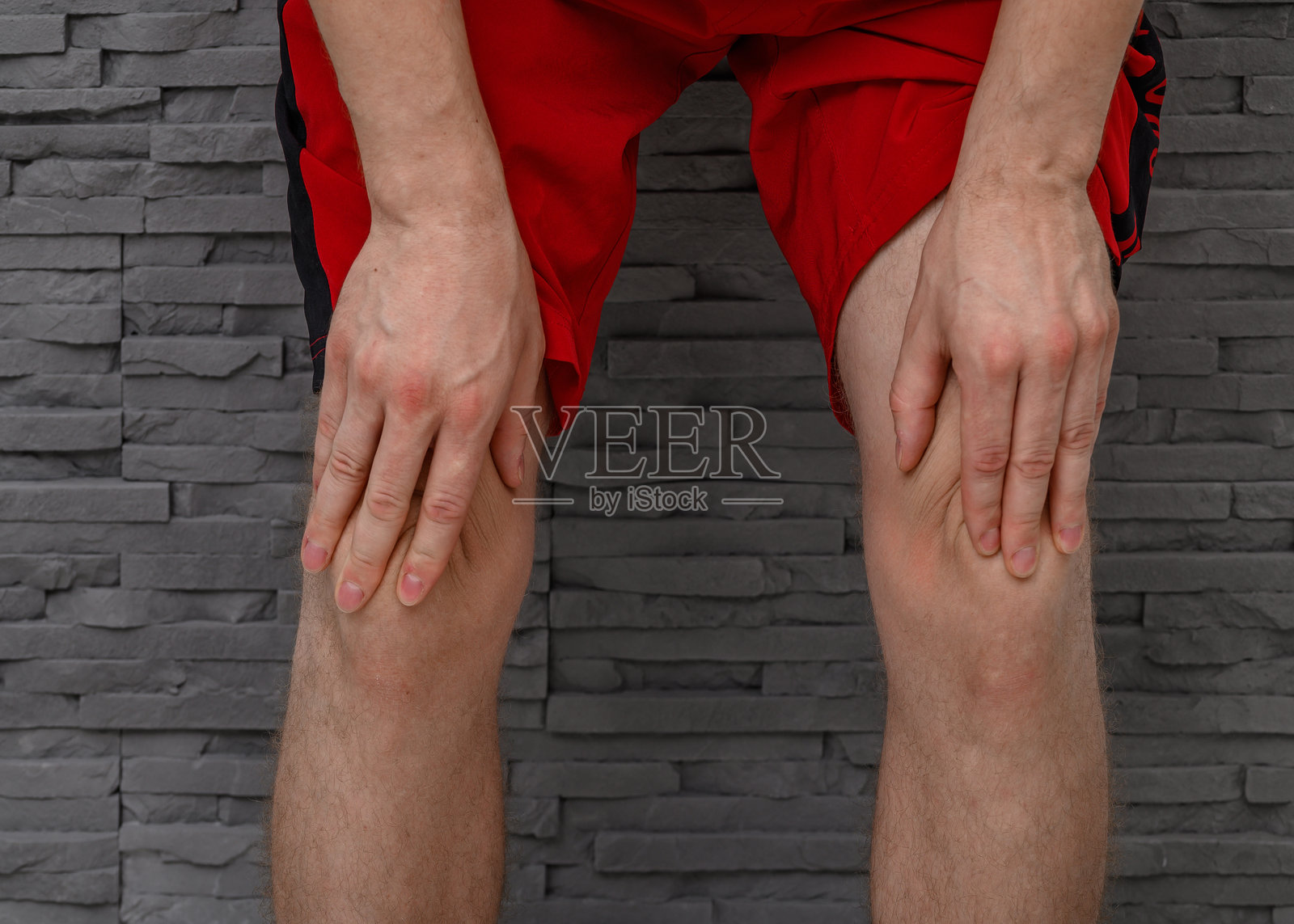 男性运动员抱着膝盖，因过度劳累而感到疼痛照片摄影图片