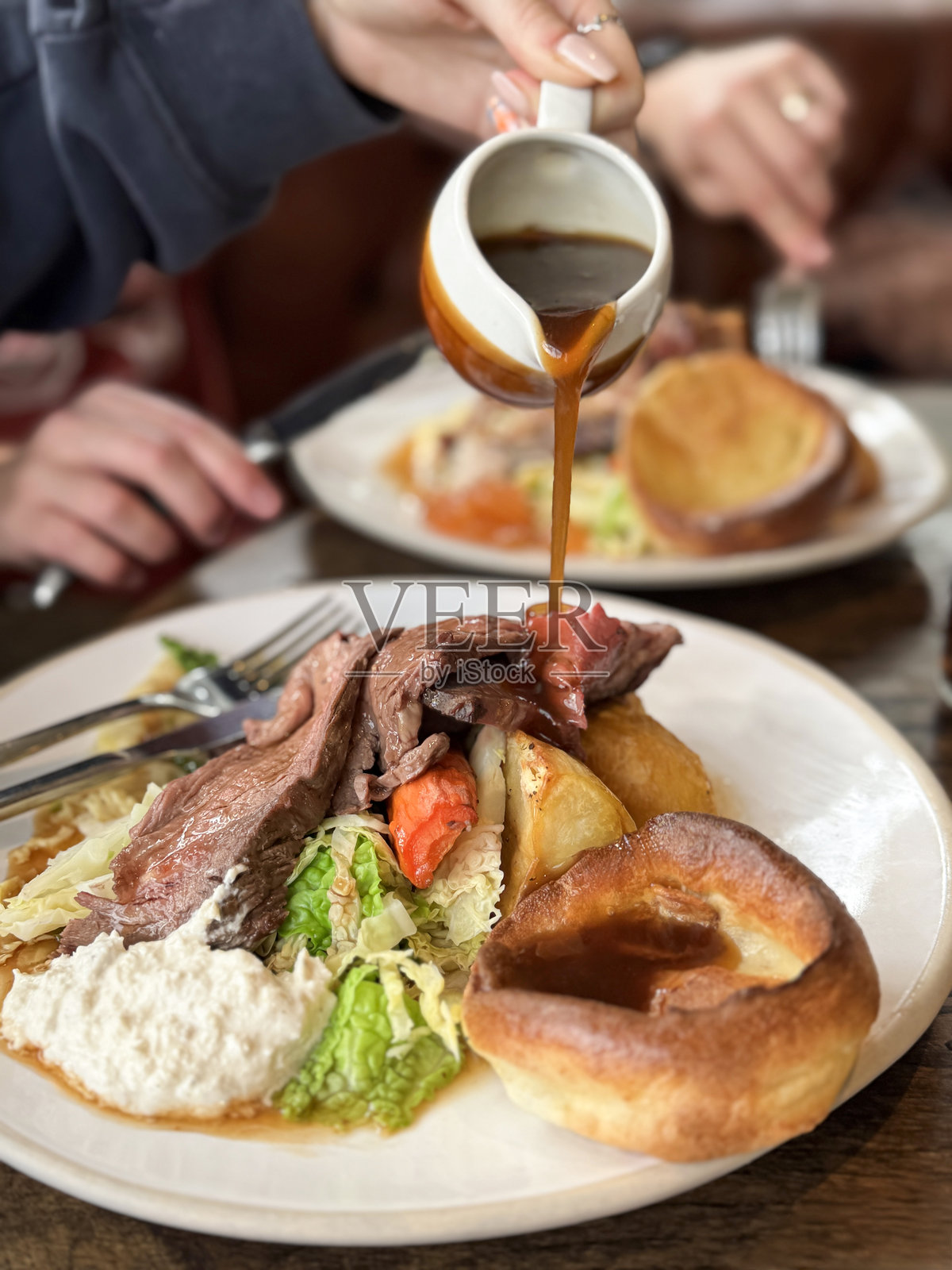 烤牛肉周日晚餐的图片/ 嫩滑的牛肉，酥脆的烤土豆，金黄的约克郡布丁，浓郁的肉汁，以及新鲜的卷心菜和胡萝卜照片摄影图片