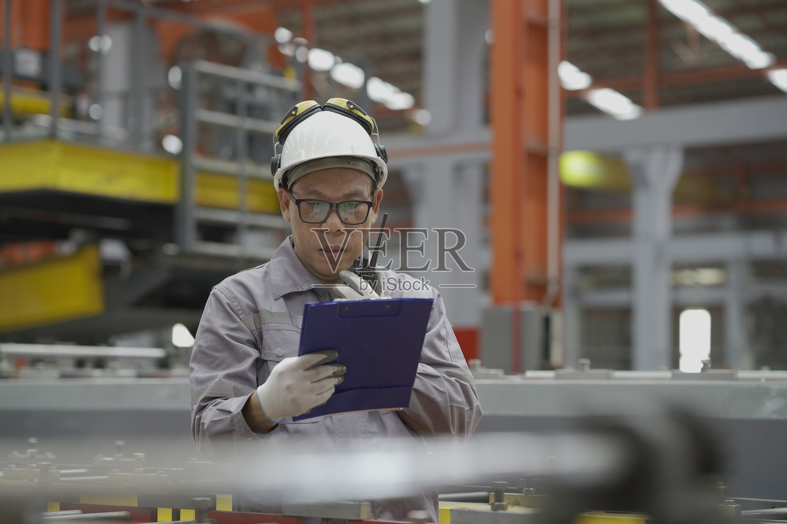 亚洲男性工人在工厂生产线上检查输送带的质量。男性工人在工厂的制造过程中操作和控制输送带。照片摄影图片