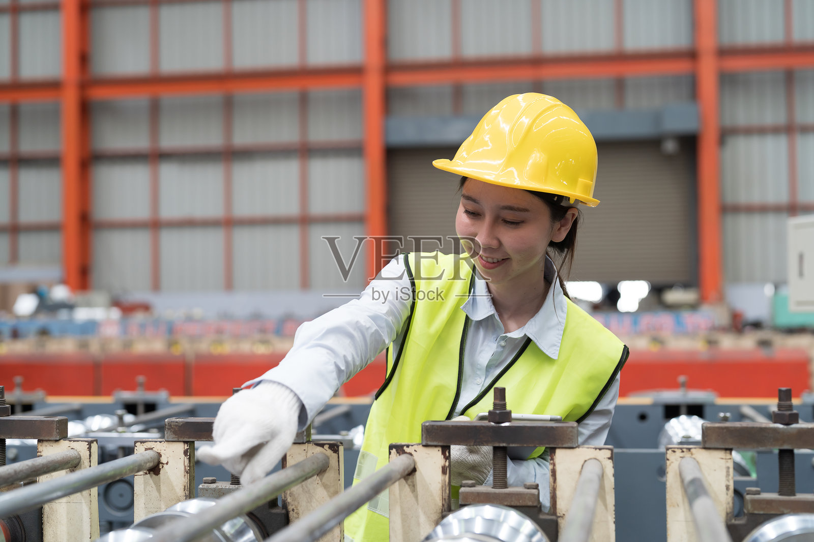 亚洲女性工人在工厂生产线上检查输送带的质量。女性工人正在工作并控制制造过程中的输送带。照片摄影图片