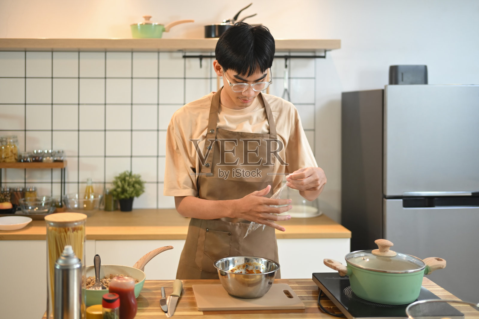 年轻的亚洲男子穿着休闲服装在厨房准备餐点照片摄影图片