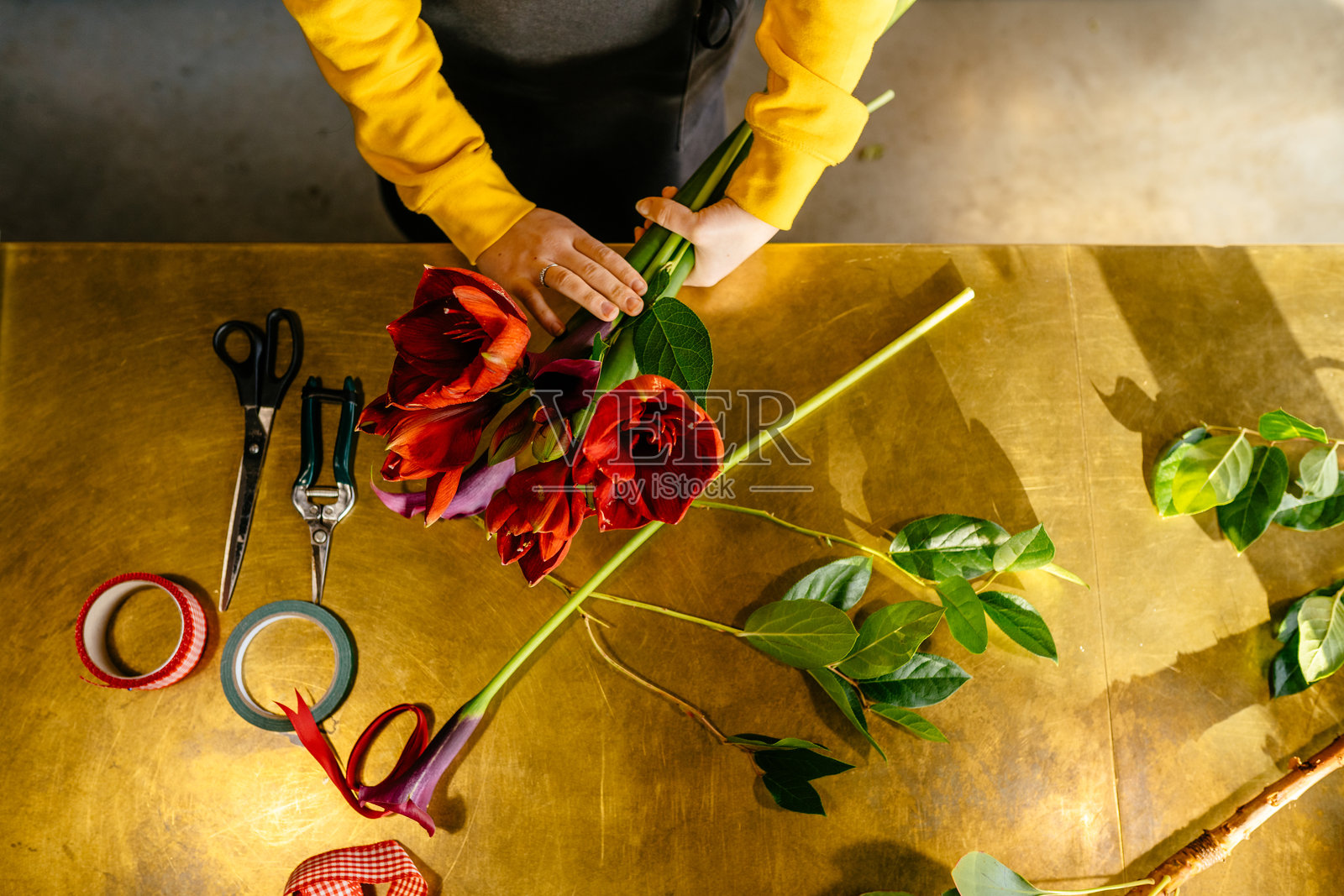高角度裁剪的视图，展示了一位不知名的助手在桌面工作台上为节日纪念日礼物设计新订单。照片摄影图片