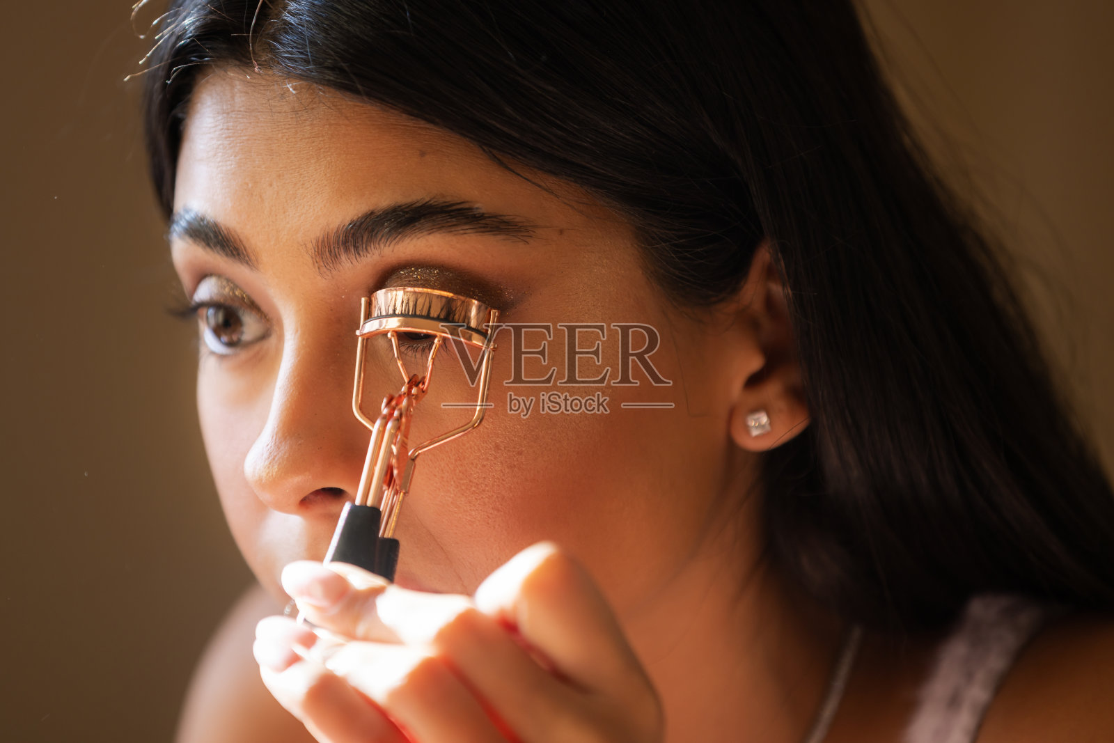 年轻女性正在使用睫毛夹。照片摄影图片